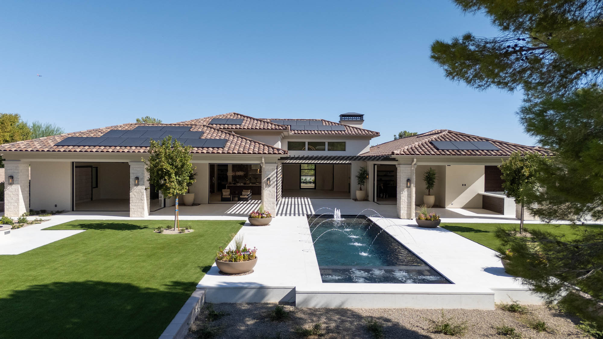 custom-new-build-southern-highlands_kingdomandco Southern Highlands backyard with central fountain, covered patio, and Mediterranean-inspired design by Kingdom & Co