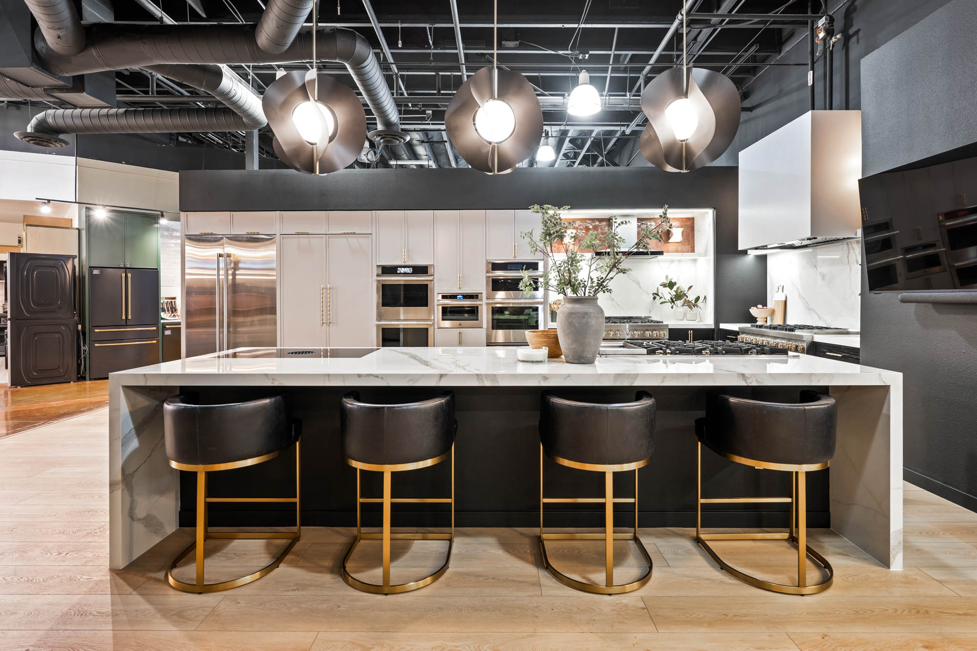 Full kitchen view with marble waterfall island, black barstools, and statement lighting designed by Kingdom & Co.