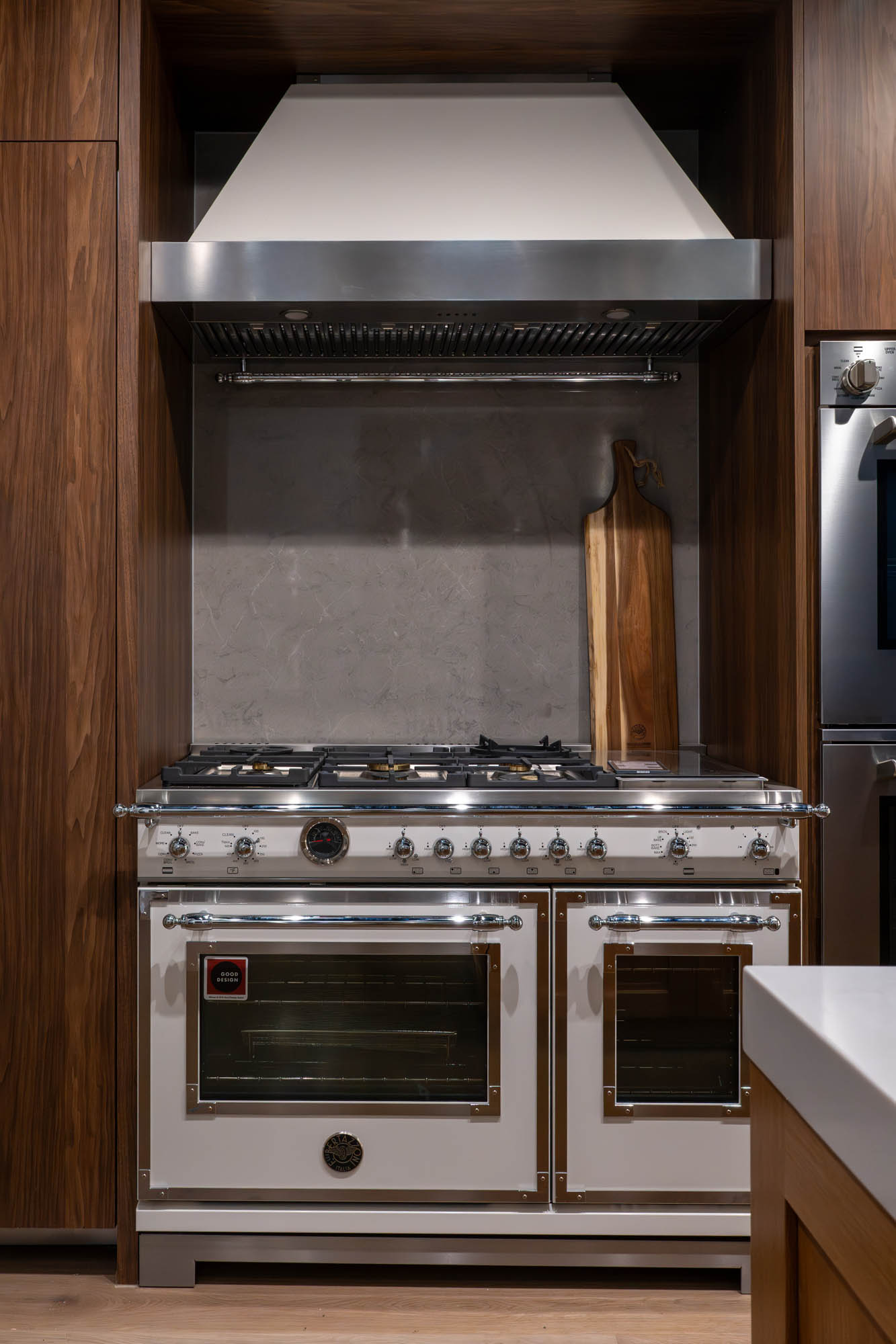 White range with chrome details set in walnut cabinetry designed by Kingdom & Co Las Vegas.