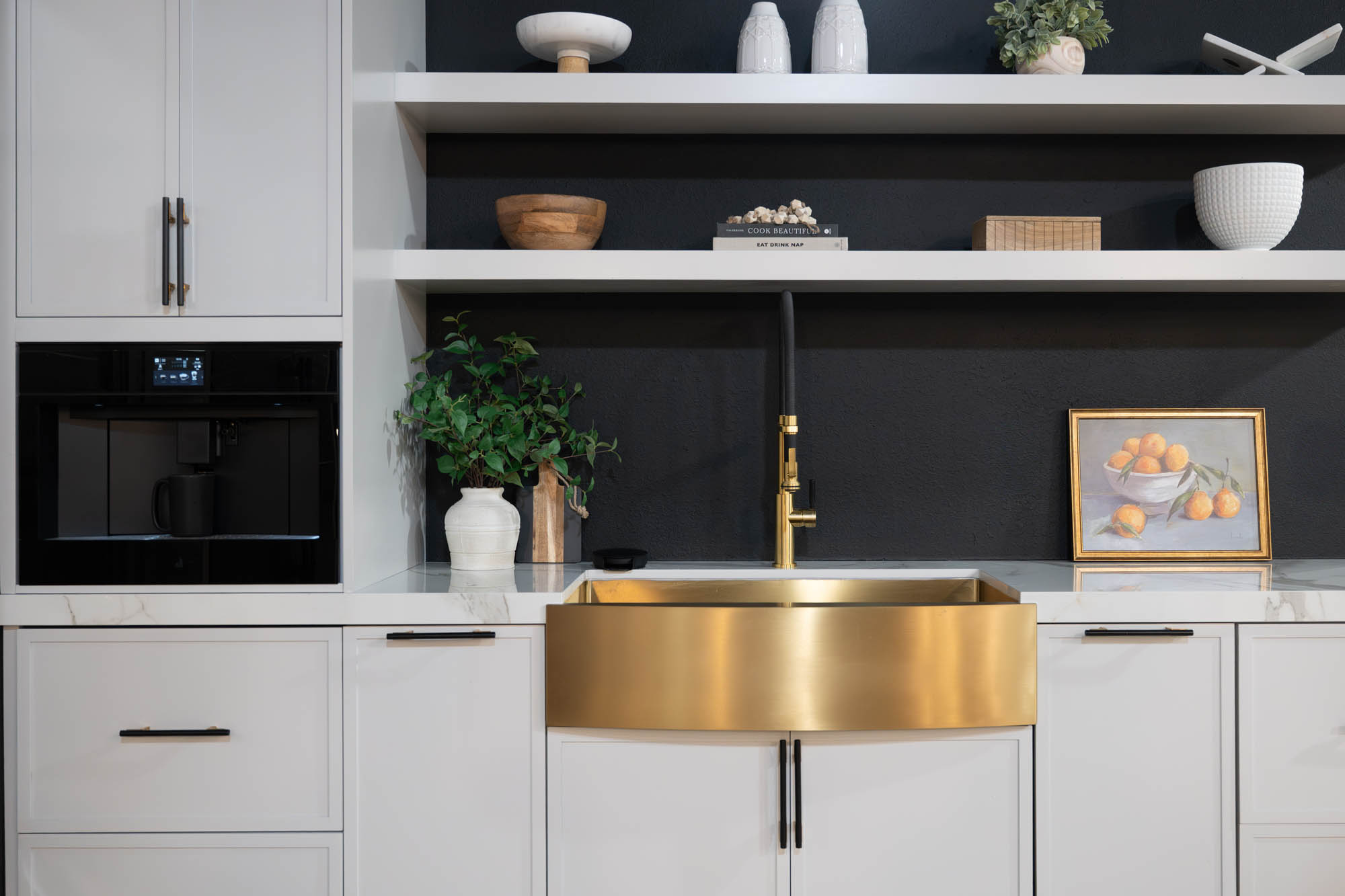 Brass farmhouse sink with matte black faucet and open shelving designed by Kingdom & Co Las Vegas.