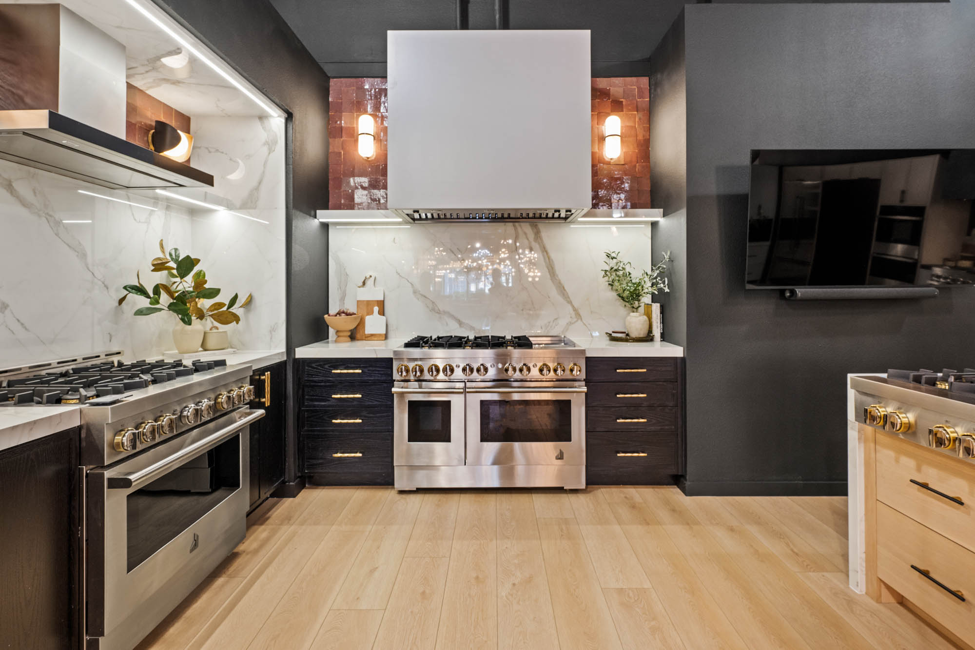 Dual professional gas ranges with marble backsplash and integrated hood in luxury kitchen by Kingdom & Co.