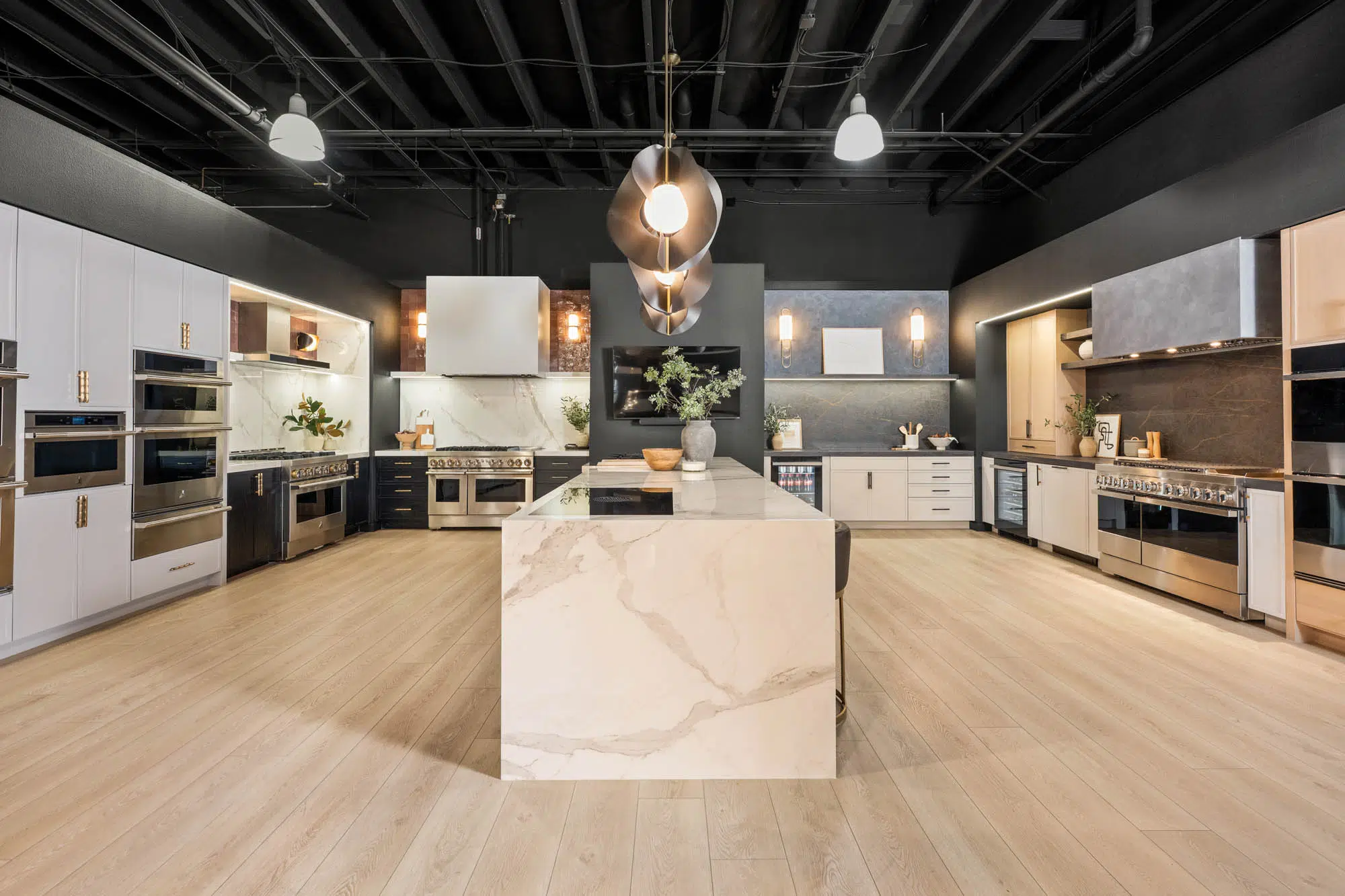 Modern showroom kitchen with marble waterfall island, dark ceilings, and brass lighting designed by Kingdom & Co Las Vegas.