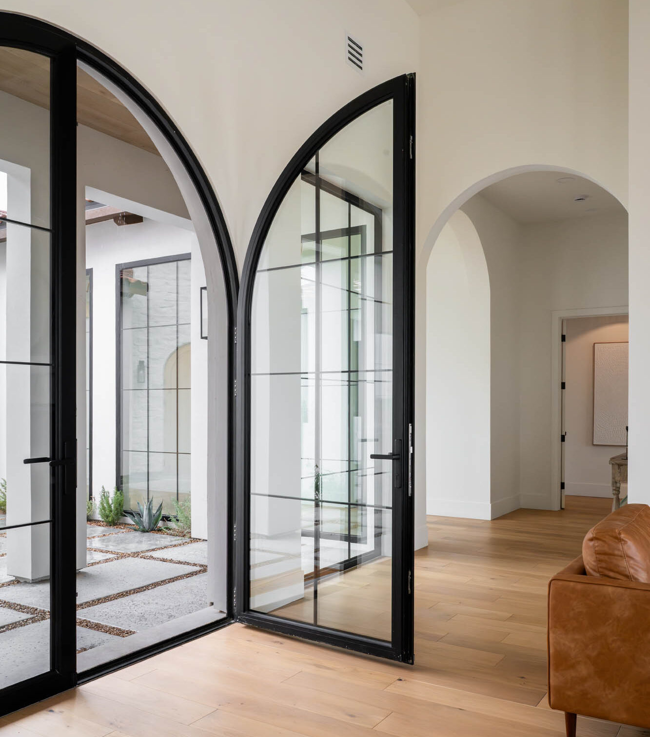 Raven-custom-glass-doors-and-windows Arched steel doors opening to desert courtyard in modern Las Vegas home