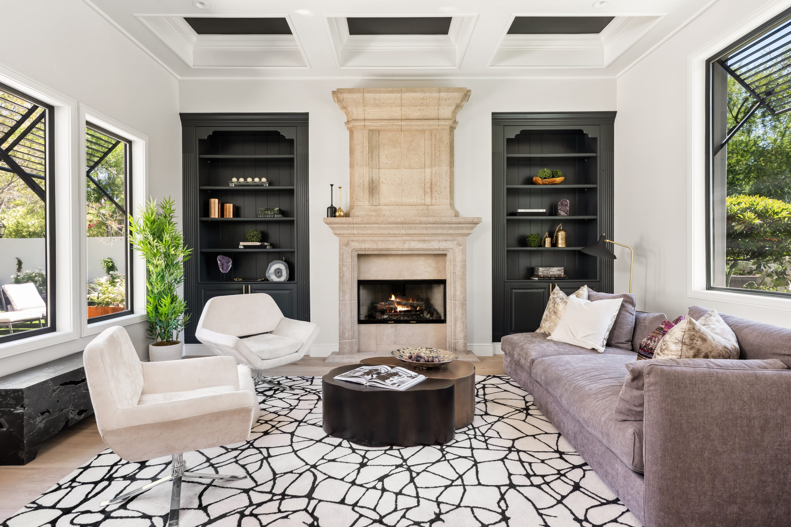The Lucida_summerlin-south_luxury-remodel_kingdomandco Elegant living room with limestone fireplace and dark built-in shelving, designed by Kingdom & Co in Summerlin South.