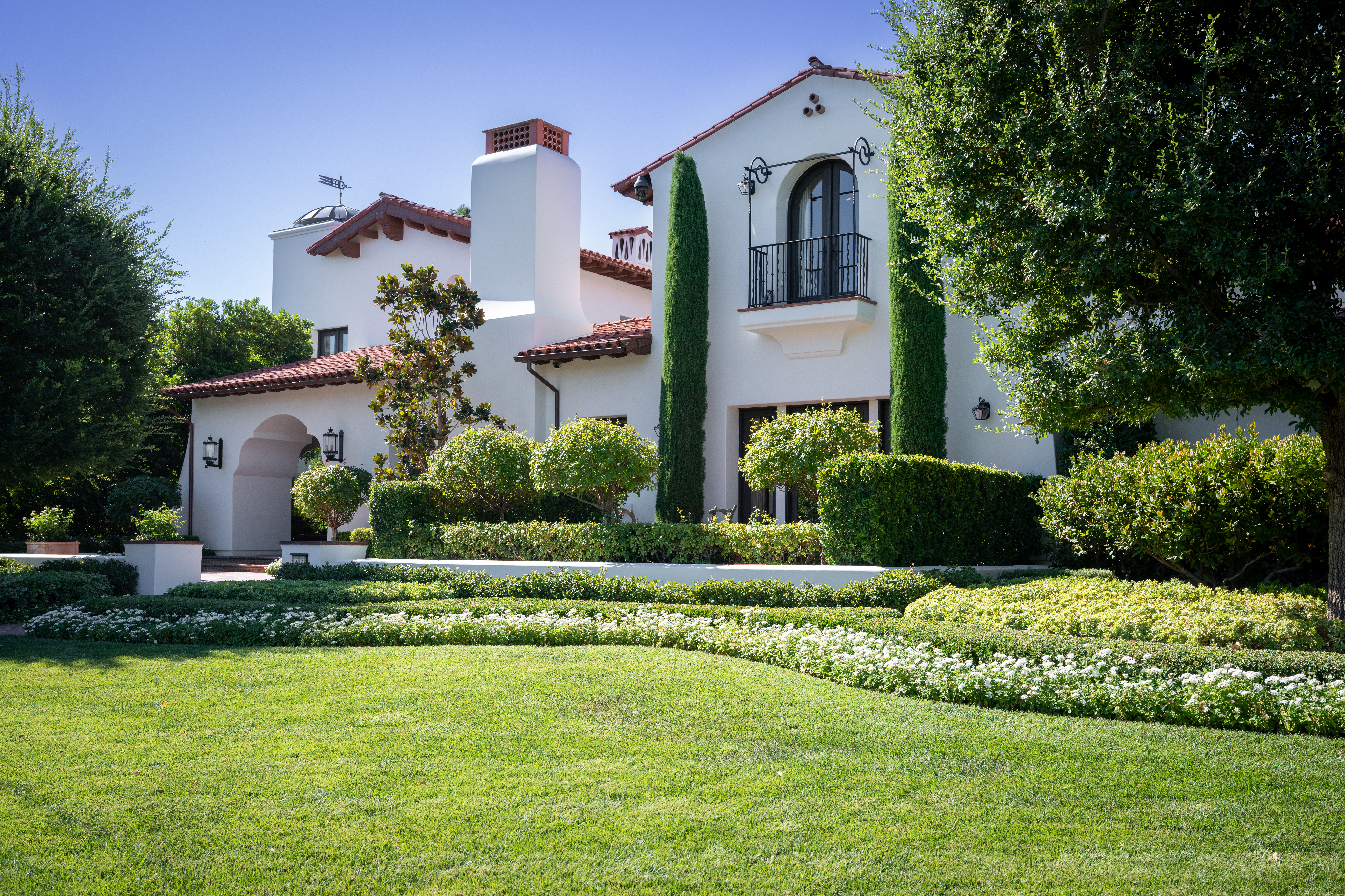Side exterior of Santa Barbara Estate with arched windows and landscaped garden