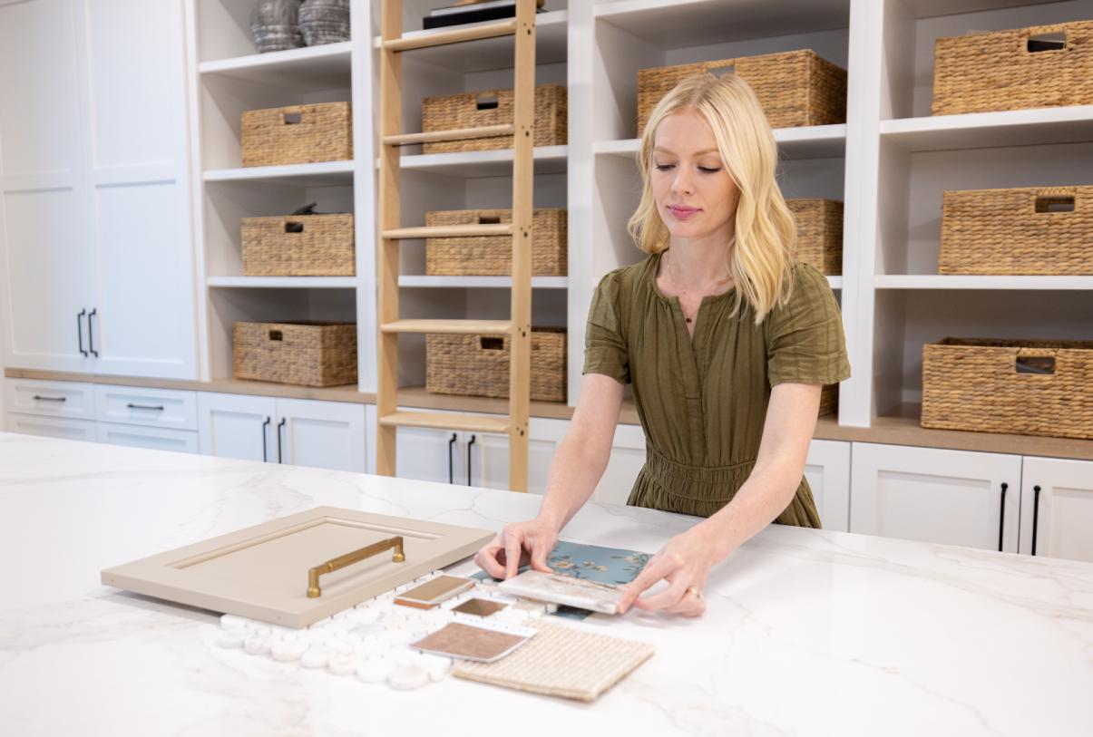 Interior designer in a design studio pairing color samples, wood and trim samples, and other design elements for interior design aesthetic.