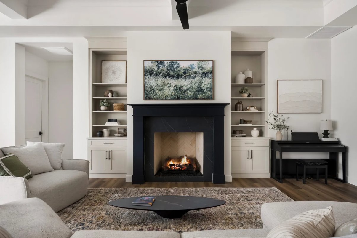 Cozy luxury living room in beige featuring black fireplace, aesthetic decor, and a plush beige sectional sofa.