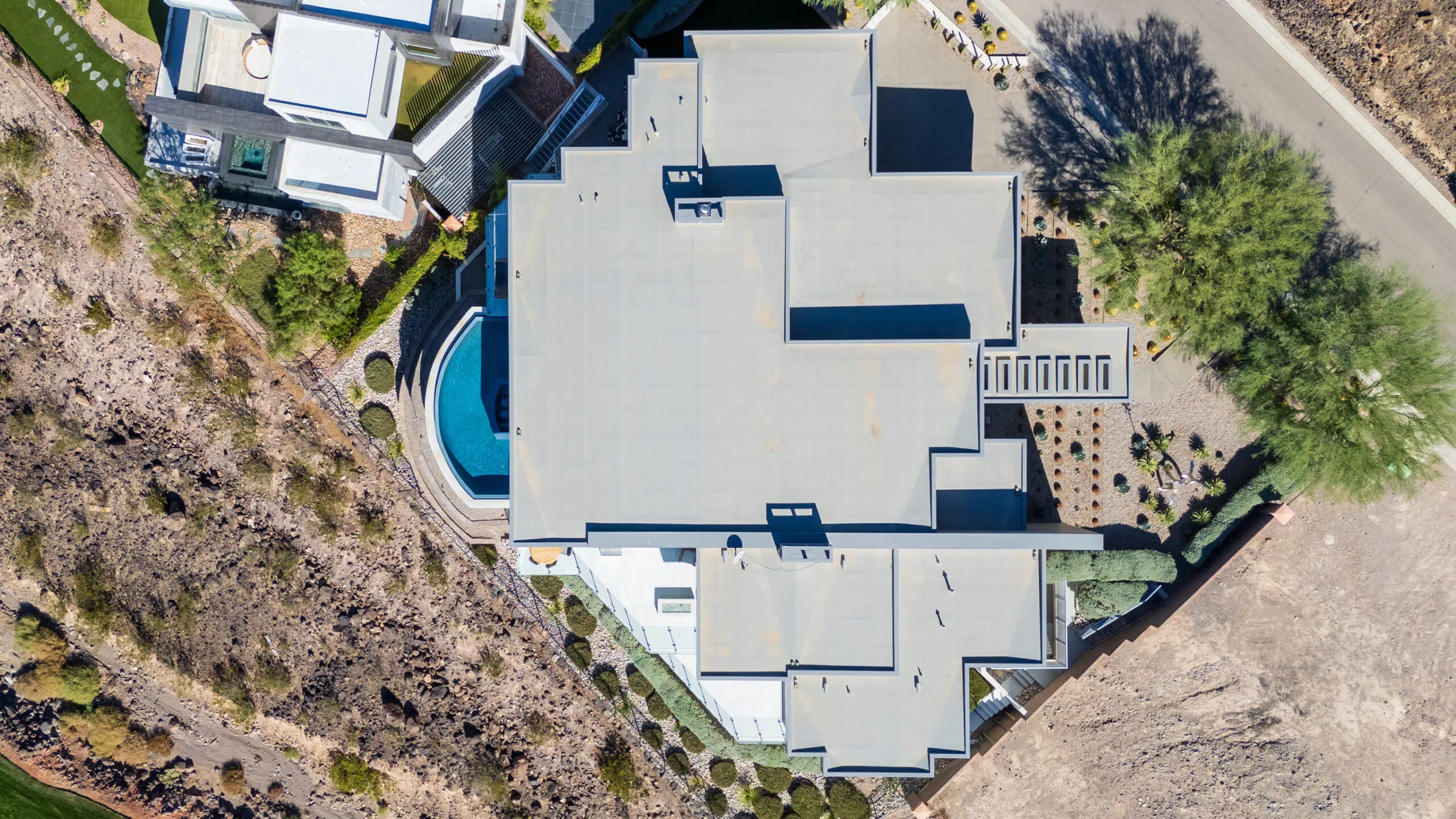 Top-down aerial of the Nova Estate showing full roof layout elevated pool desert landscaping and driveway in MacDonald Highlands Henderson
