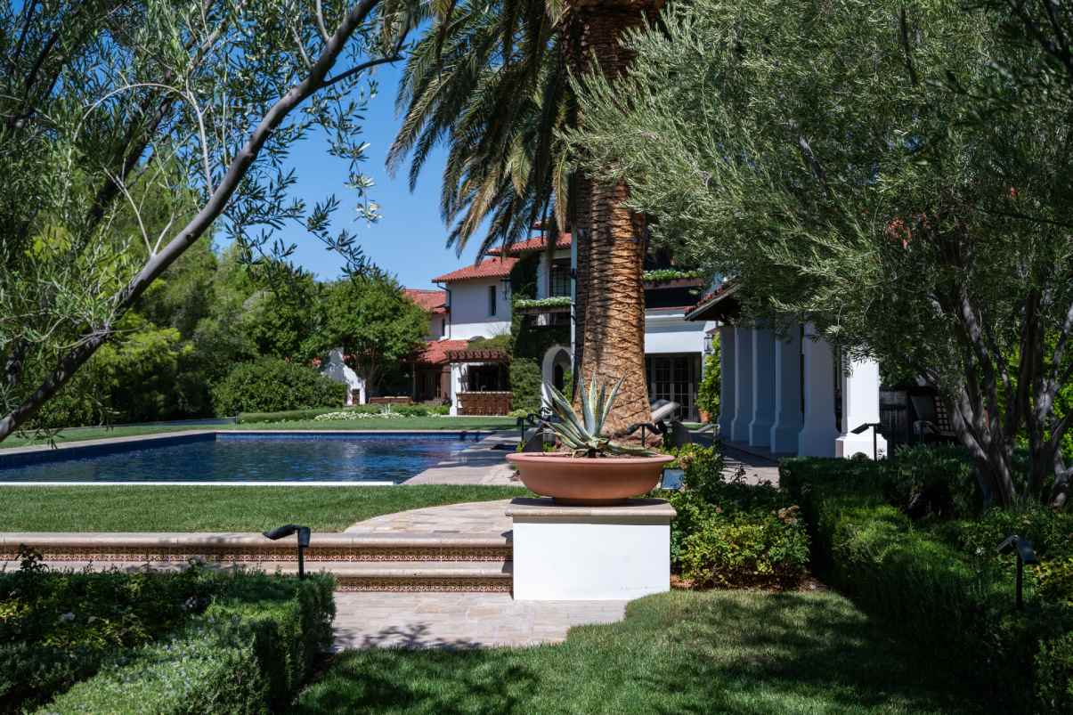 A luxury home’s backyard in Santa Barbara with pool, landscaping, and palm trees.