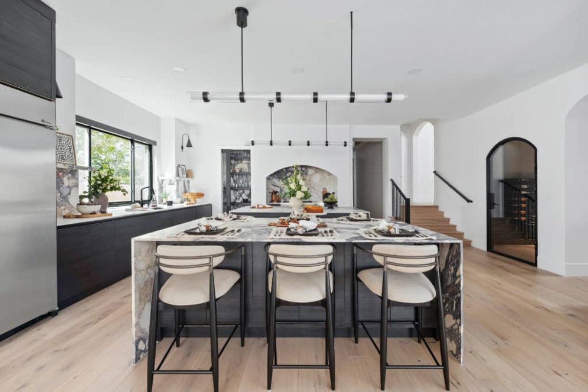 Luxury kitchen featuring modern black and white aesthetic, large eat-in island, and airy layout.