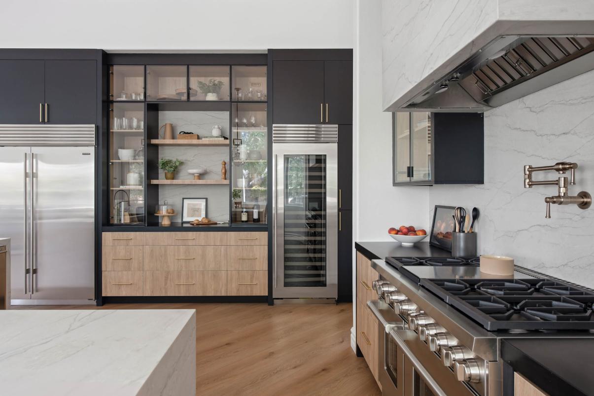 Upscale modern kitchen featuring premium appliances, marble backsplash, dark cabinets, and wooden accents.