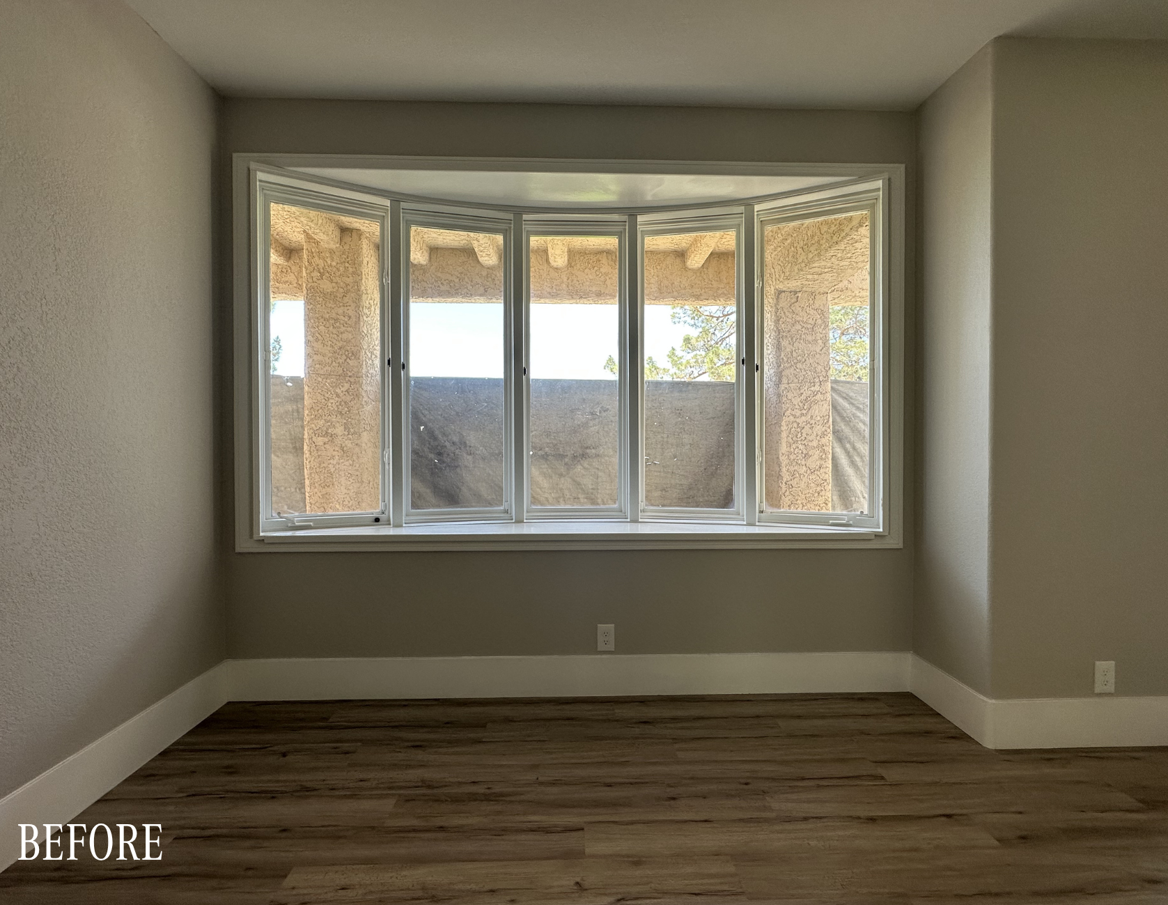 Before: Curved bay window area with carpet flooring and green walls before The Parker kitchen remodel