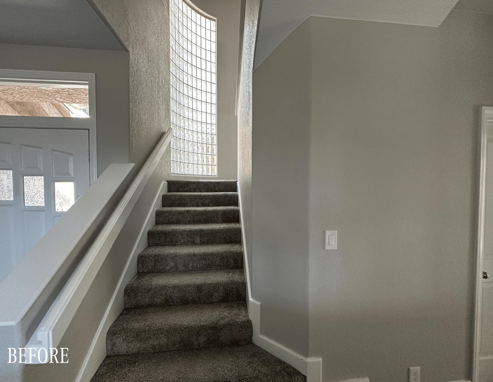 Before: Plain carpeted staircase with white painted railings and frosted glass block window before The Parker remodel