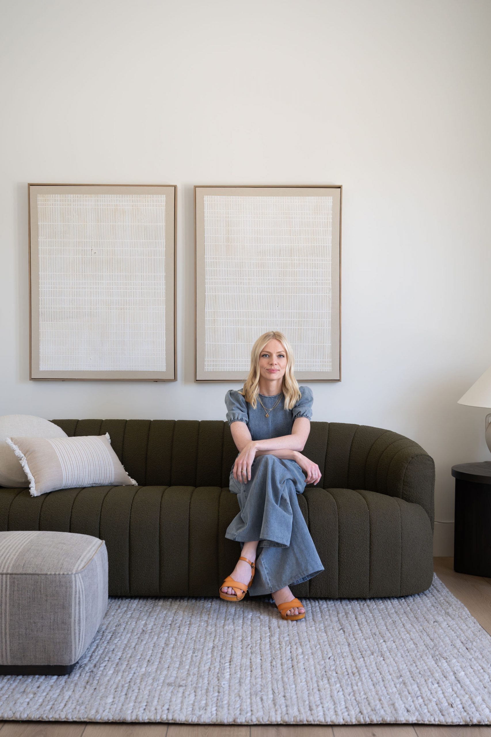 Lifestyle vignette with dark green boucle sofa, white striped accent pillow, and twin framed linen artwork in natural wood frames at Magnolia Heights Estate Las Vegas