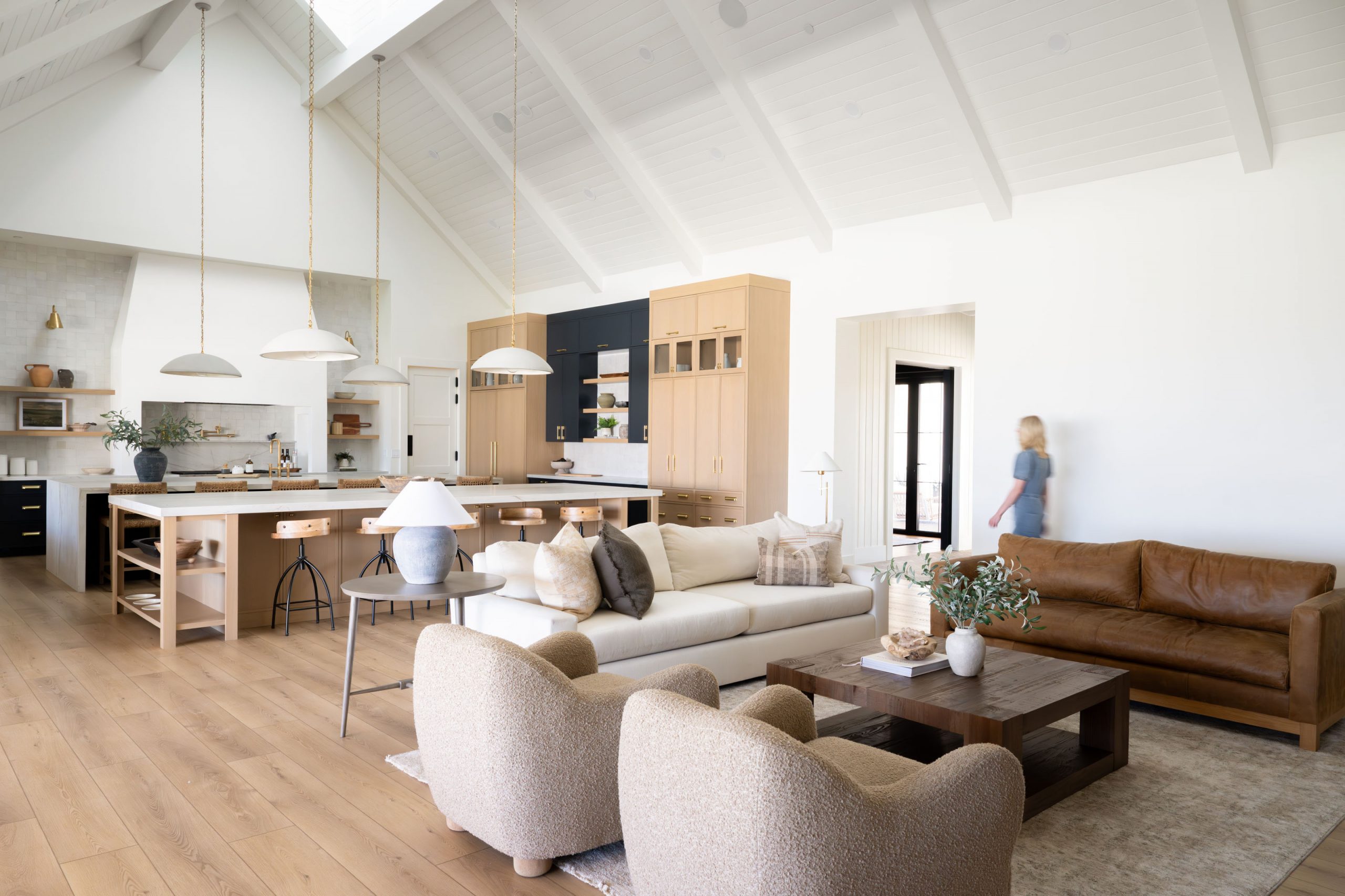 Elevated view of the open-concept great room with tongue and groove vaulted ceiling, reclaimed wood beams, dome pendant lights on brass chains, and navy kitchen island in this modern traditional custom home Las Vegas project at Magnolia Heights Estate