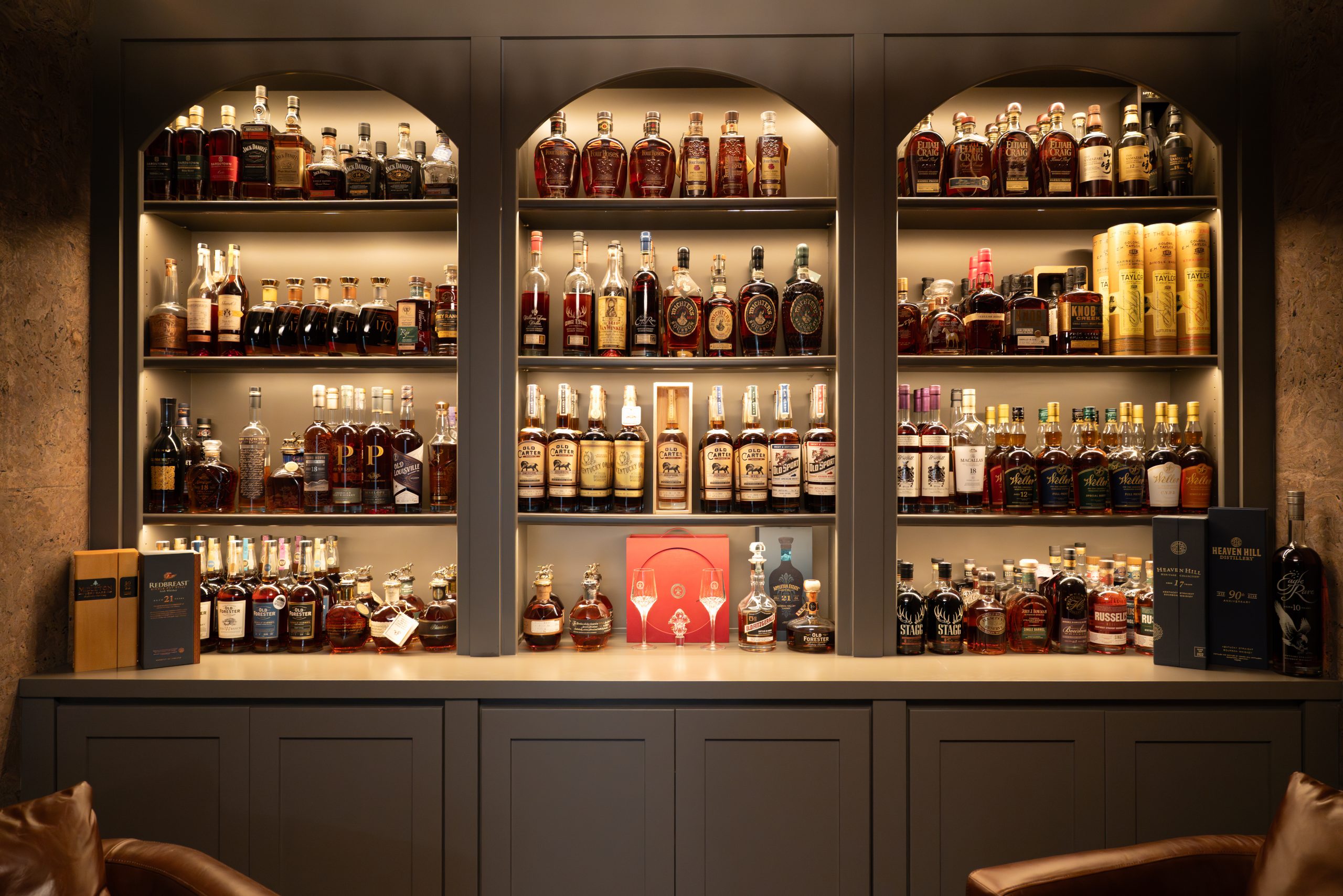 The Charleston_048 Three arched custom whiskey display cabinets with backlit shelving and a curated bourbon collection at The Charleston Southern Highlands remodel whiskey lounge.