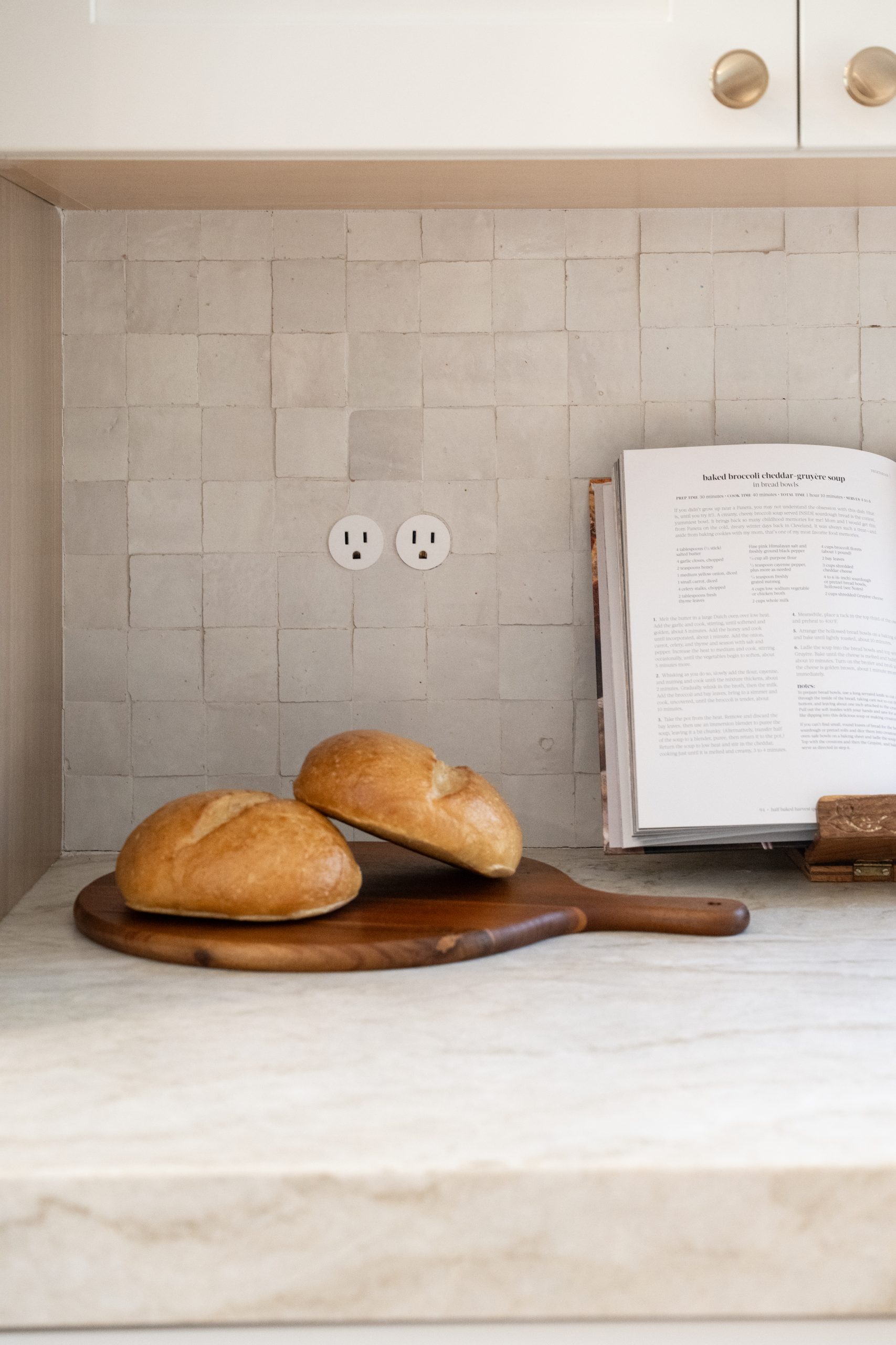 Zellige tile backsplash detail with white marble countertop, wooden bread board, and open cookbook on a custom stand at The Charleston Southern Highlands remodel.