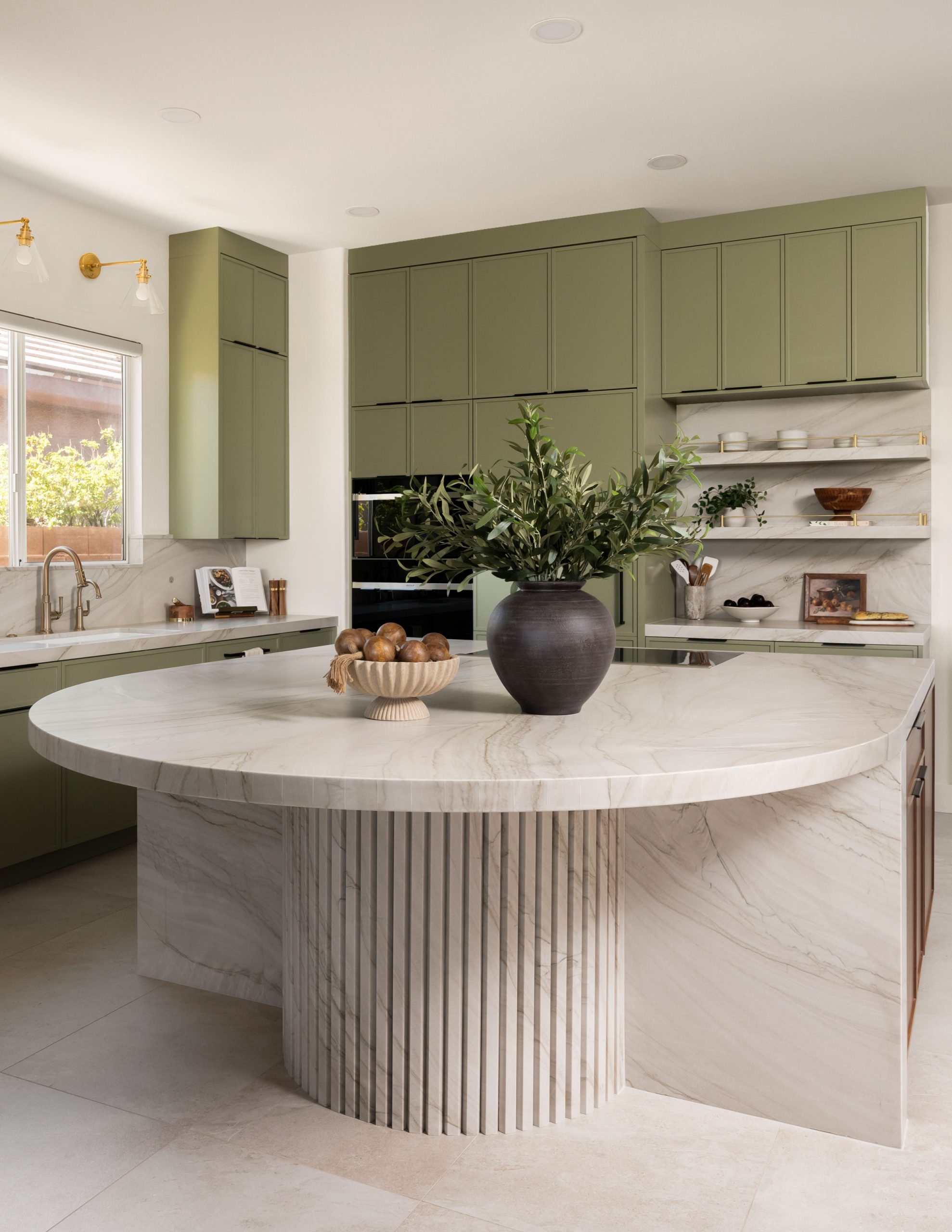 Curved marble island with olive branches and sage green cabinetry, Summerlin kitchen remodel by Kingdom & Co.