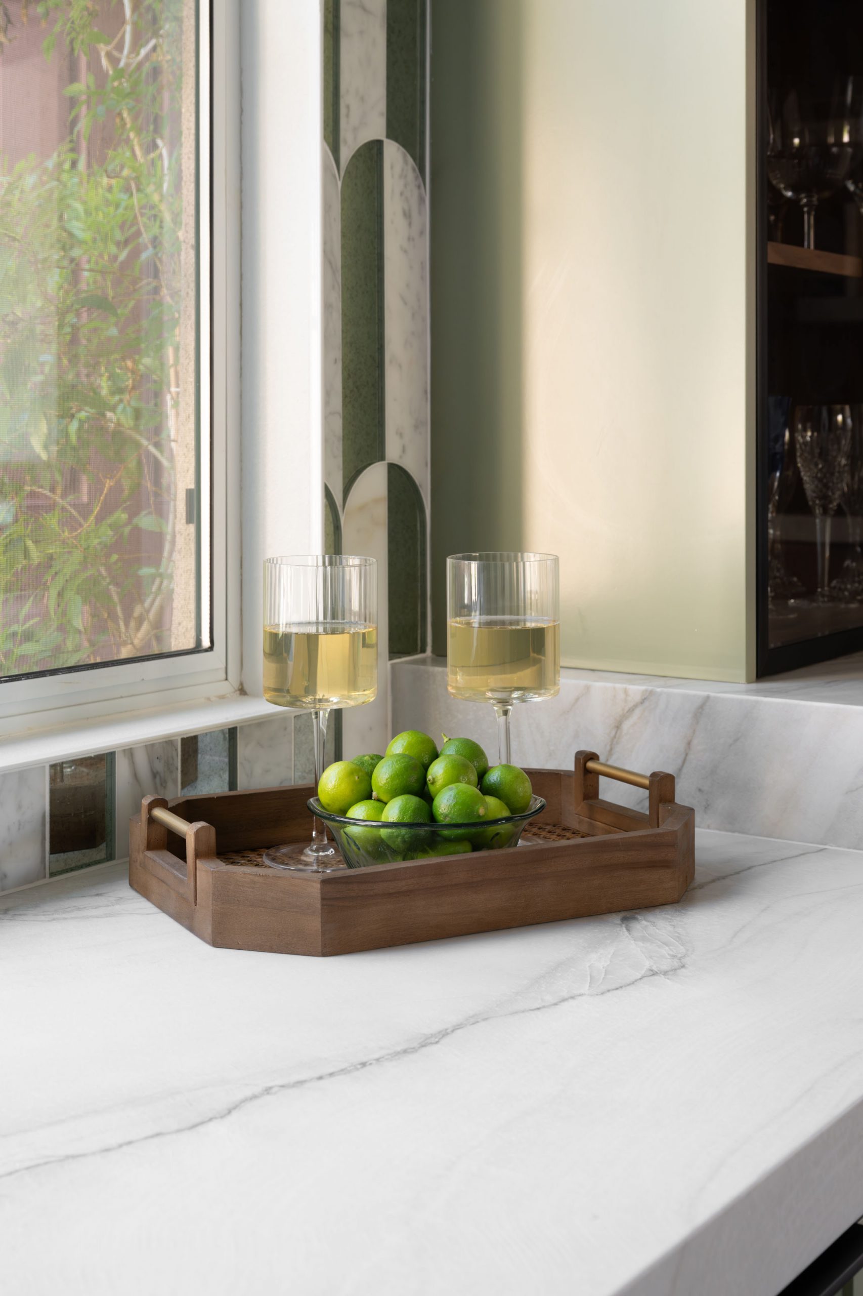 Wine glasses on wood tray at wet bar with arched green tile, Summerlin kitchen remodel by Kingdom & Co.
