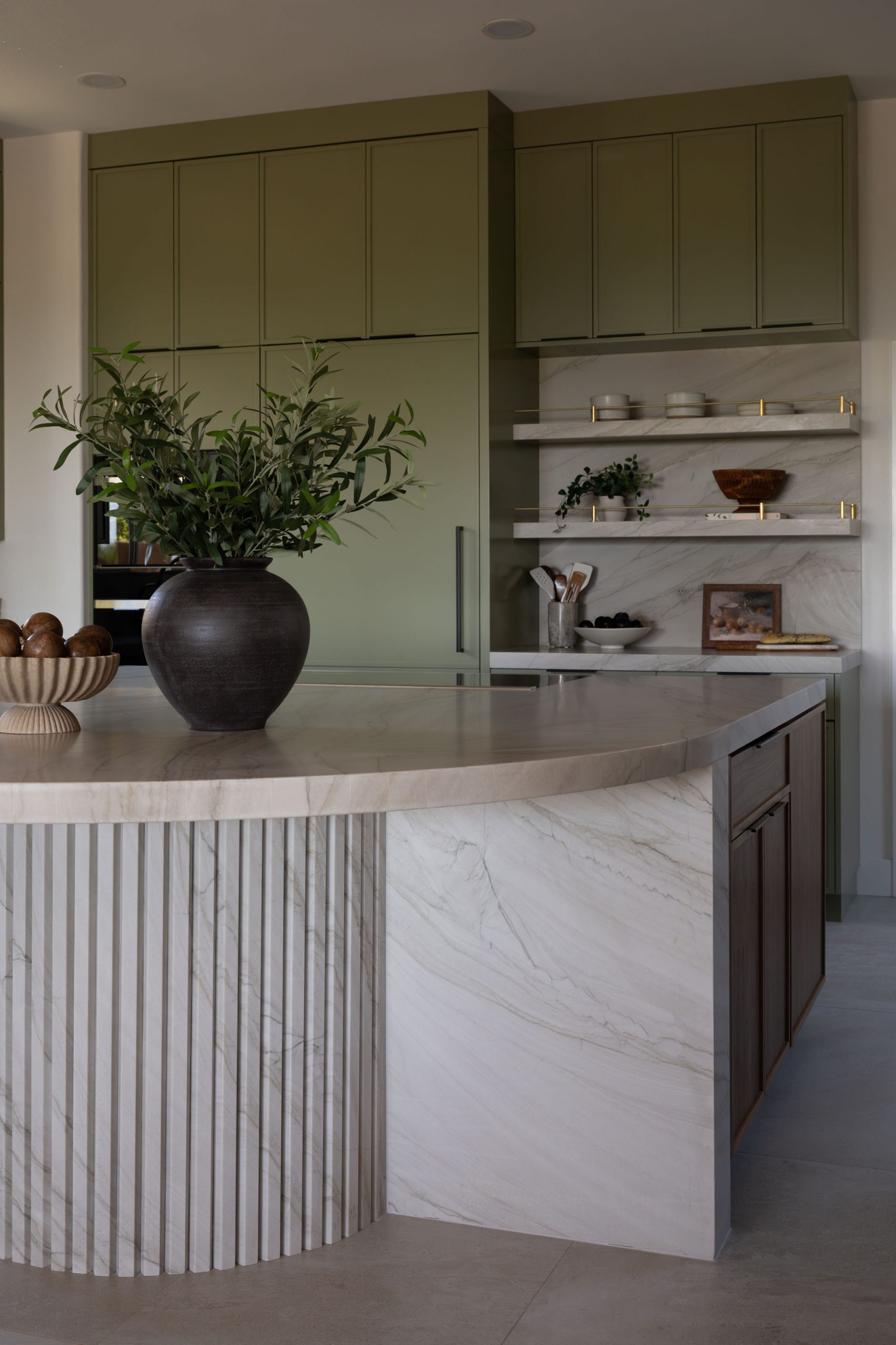 Curved fluted marble island detail with olive branches and sage cabinets, Kingdom & Co. Summerlin kitchen.