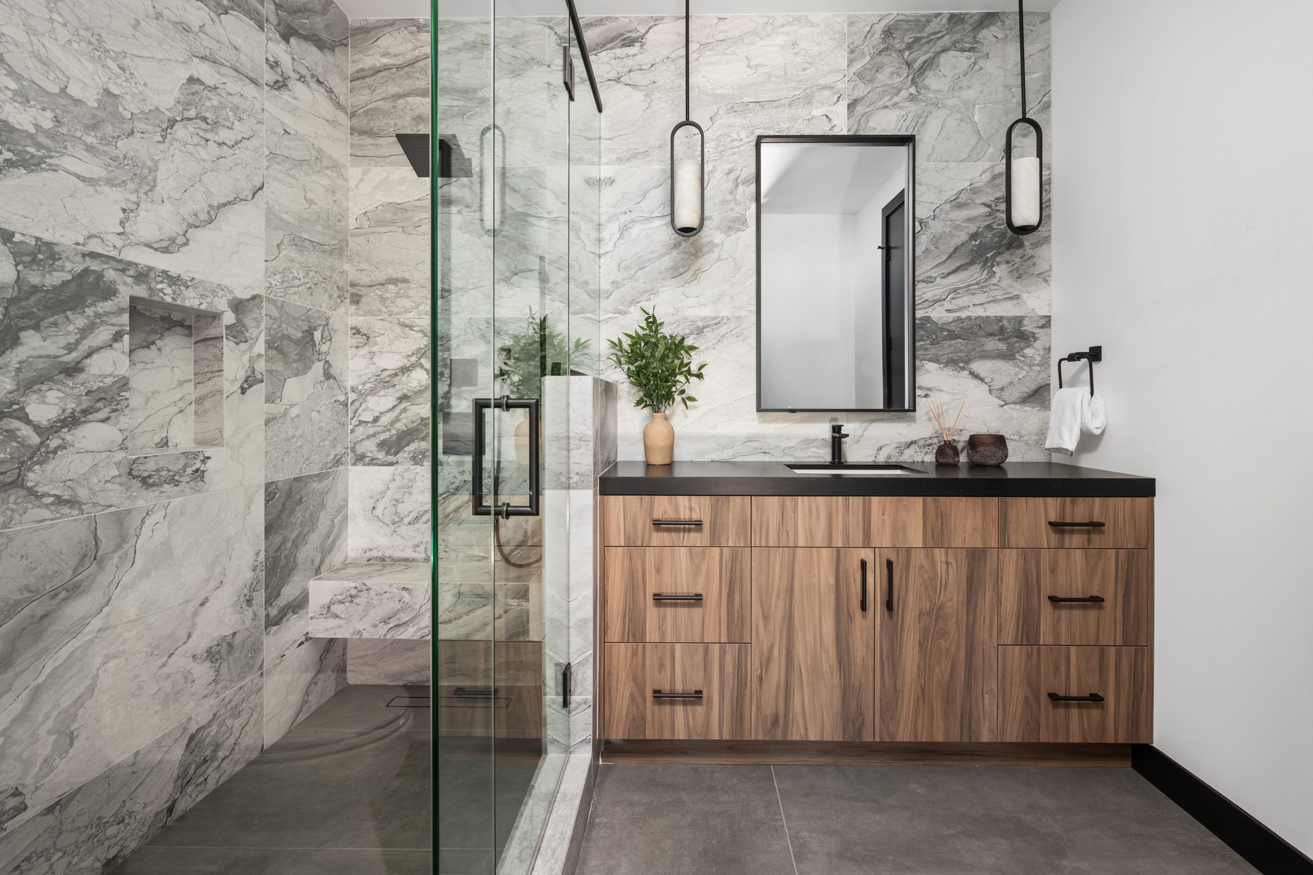 Guest bathroom with book-matched marble shower, walnut vanity, and black pendants, Kingdom & Co. The Lakes remodel.