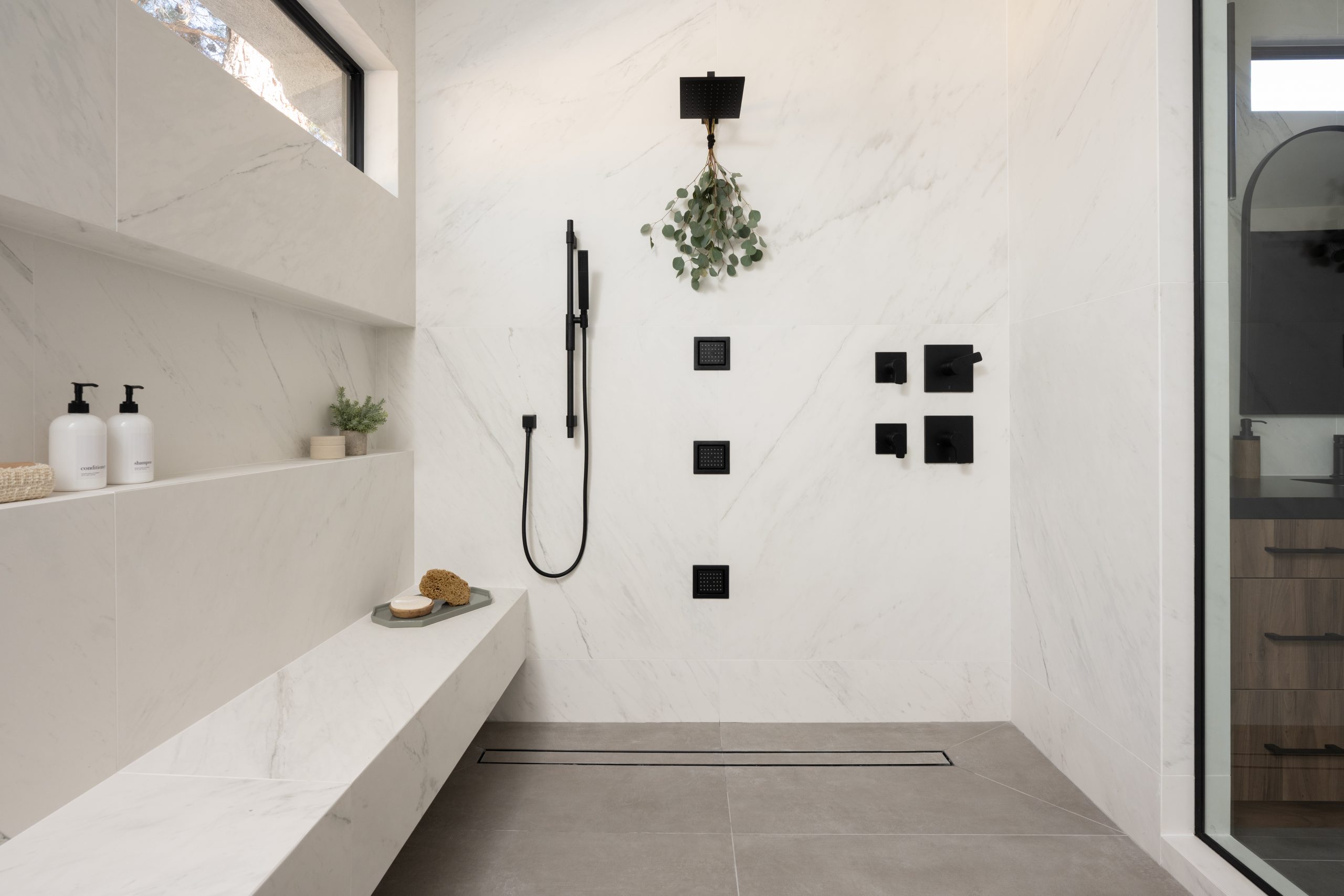 Primary bath wet room detail with marble bench and rain shower, Kingdom & Co. The Lakes remodel.