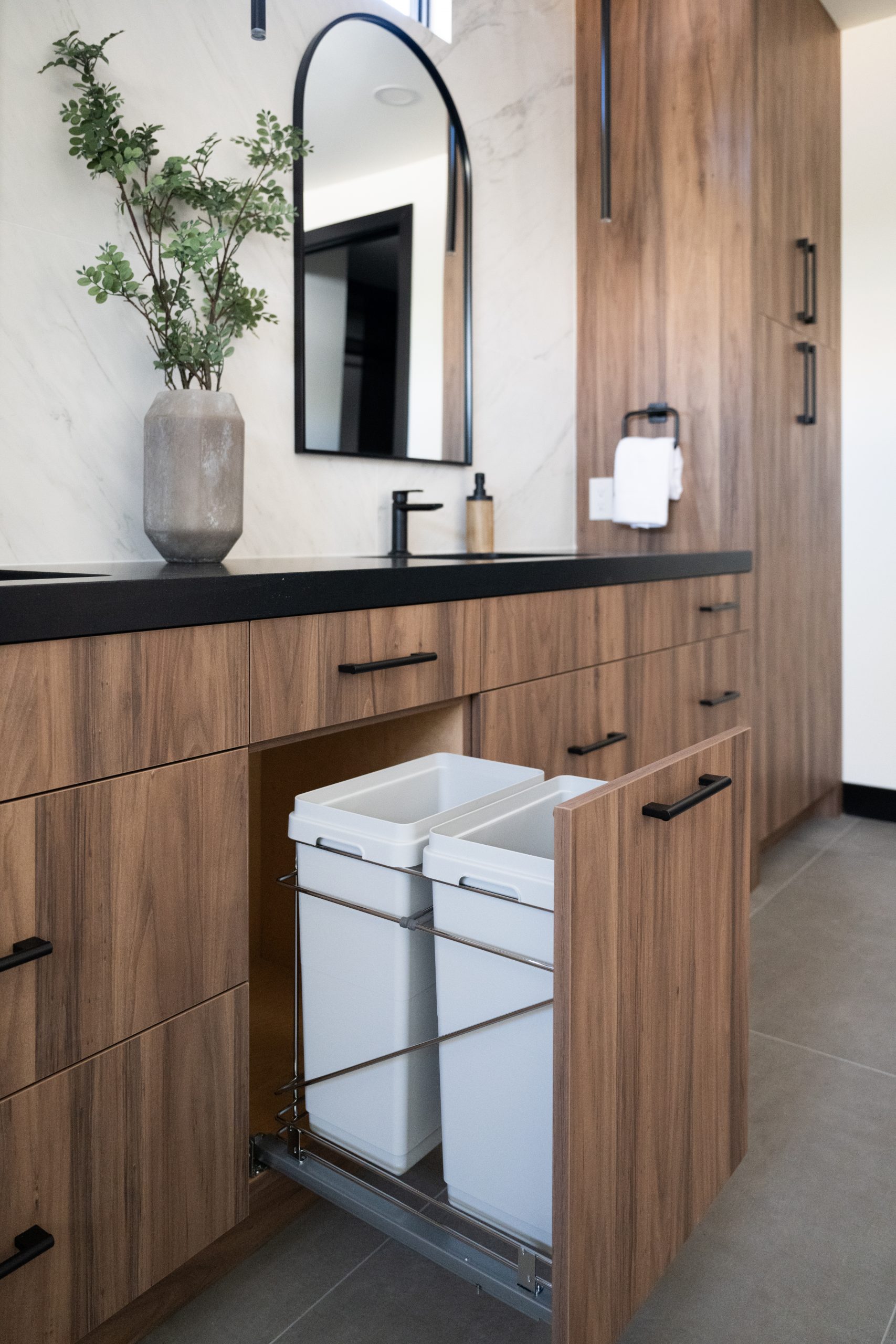 Primary bath walnut vanity with hidden pull-out trash and recycling drawer, Kingdom & Co. The Lakes remodel.