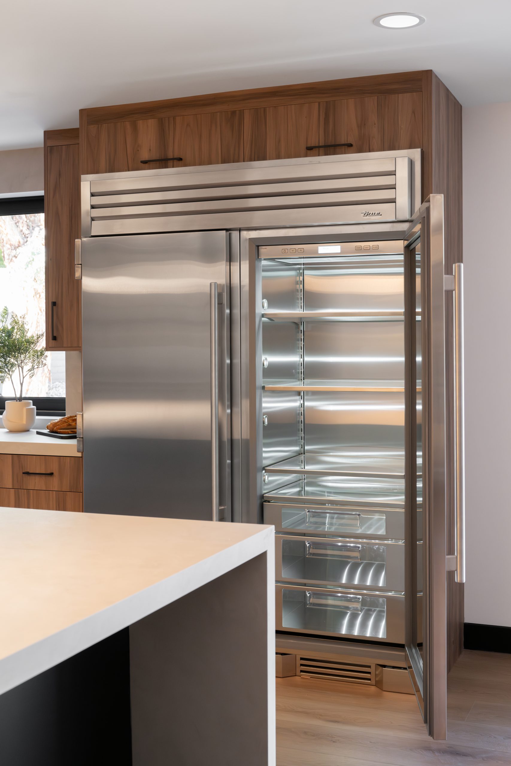 True Residential glass-door refrigerator and freezer column integrated in walnut cabinetry, Kingdom & Co. The Lakes.