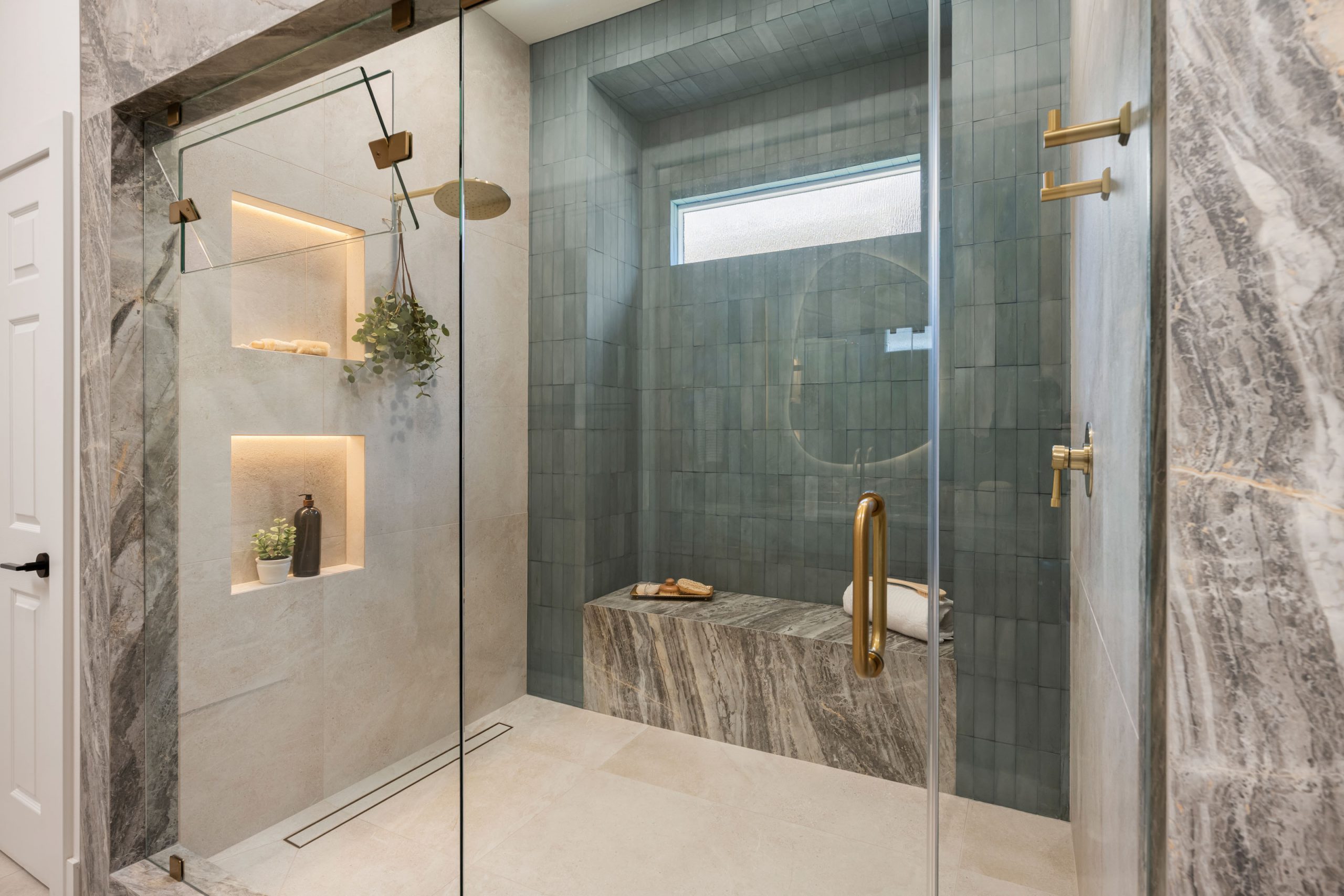 The Astoria_SummerlinRemodel Walk-in shower with stone bench, blue tile back wall, and backlit niches in Summerlin bath by Kingdom & Co.