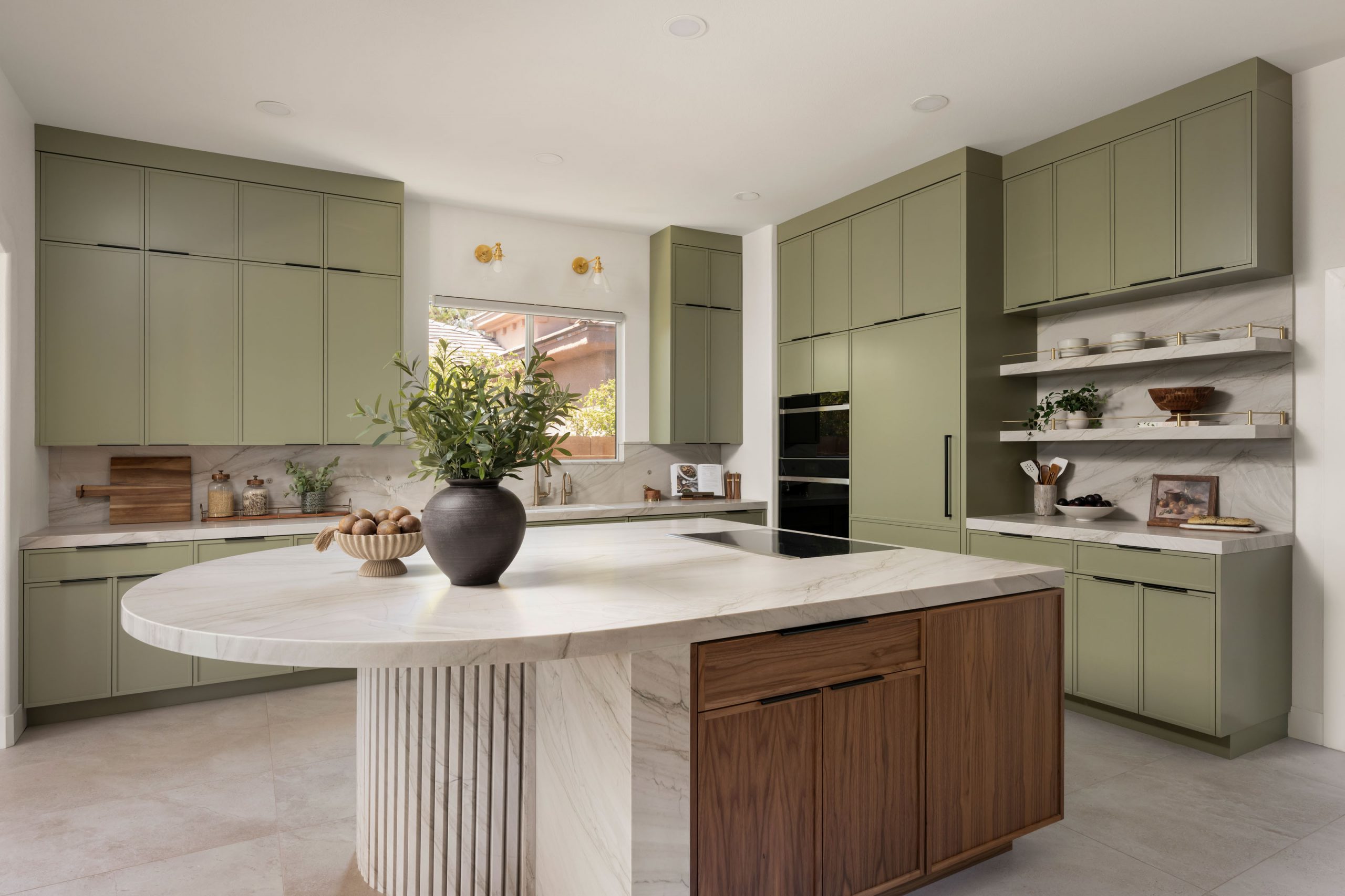 The Astoria_SummerlinRemodel Sage green kitchen with curved marble island and integrated Wolf ovens, Summerlin remodel by Kingdom & Co.