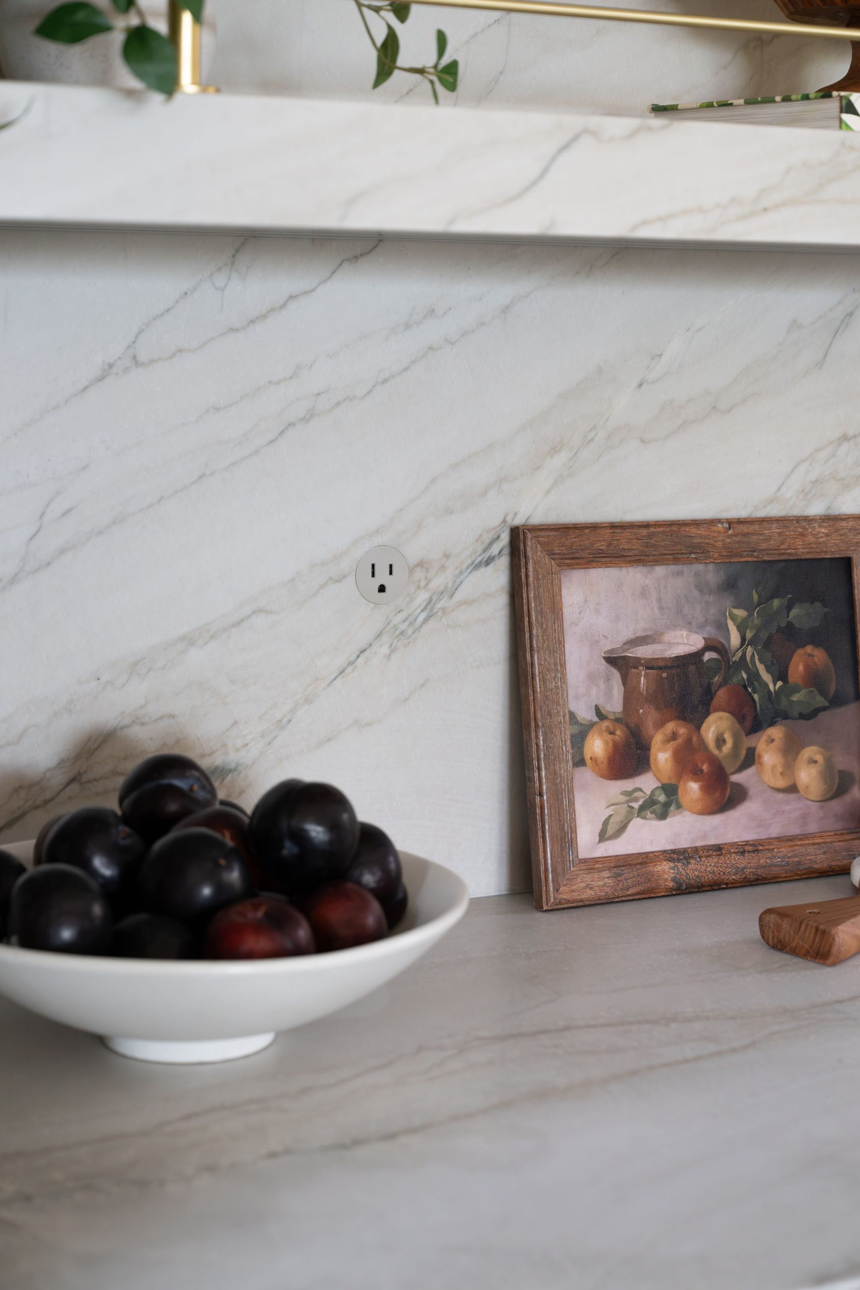 The Astoria_SummerlinRemodel Marble backsplash detail with plums and still-life art in sage kitchen remodel by Kingdom & Co.