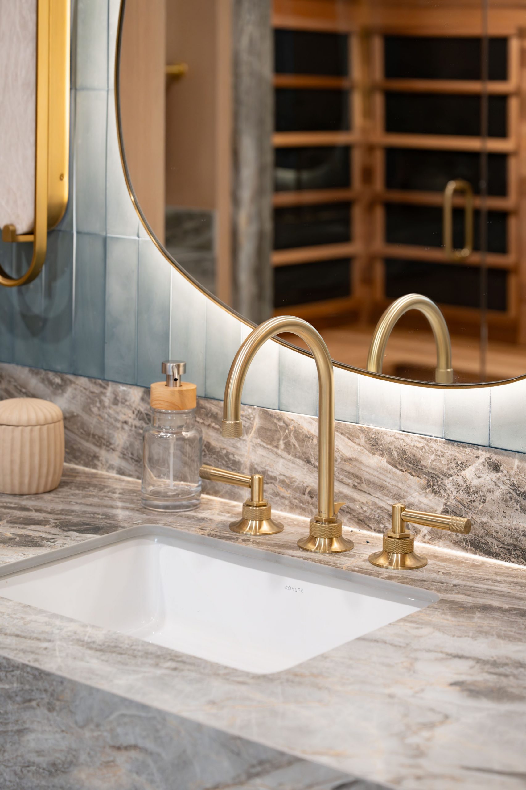 Close-up of brass Kohler faucet on grey stone vanity in Summerlin primary bath by Kingdom & Co.
