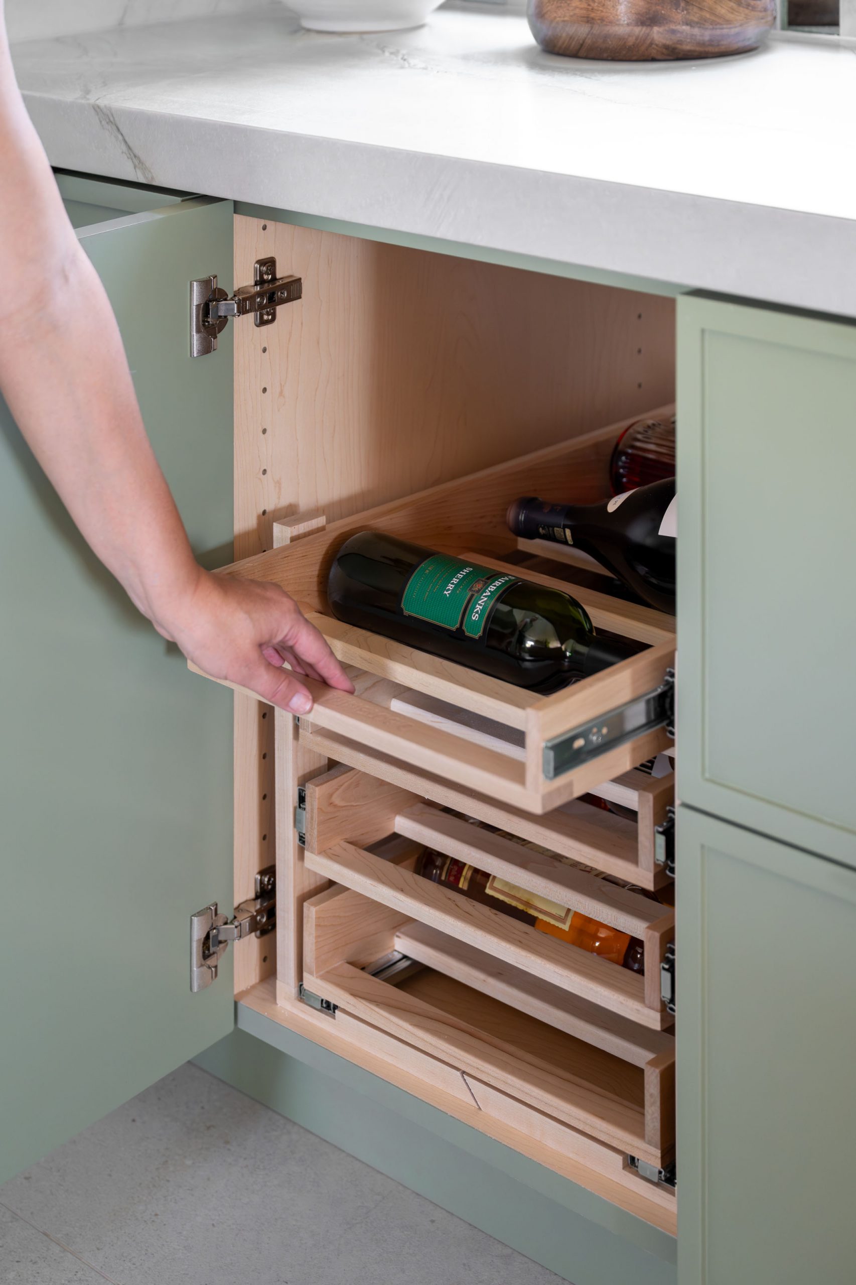 the-astoria_summerlinremodel Custom pull-out wine bottle storage inside sage green cabinet, Summerlin kitchen by Kingdom & Co.