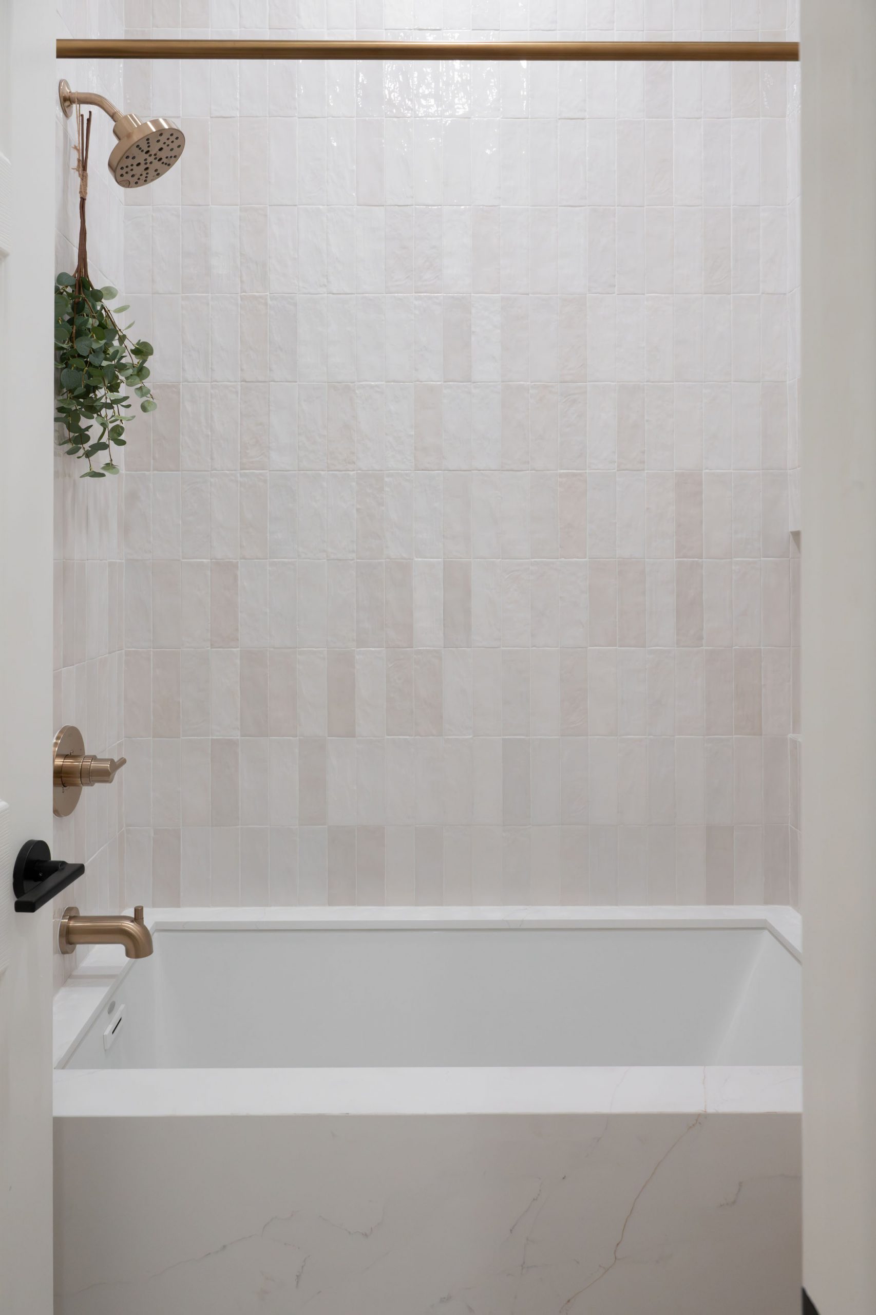White zellige tile shower over drop-in tub in Summerlin guest bath by Kingdom & Co.