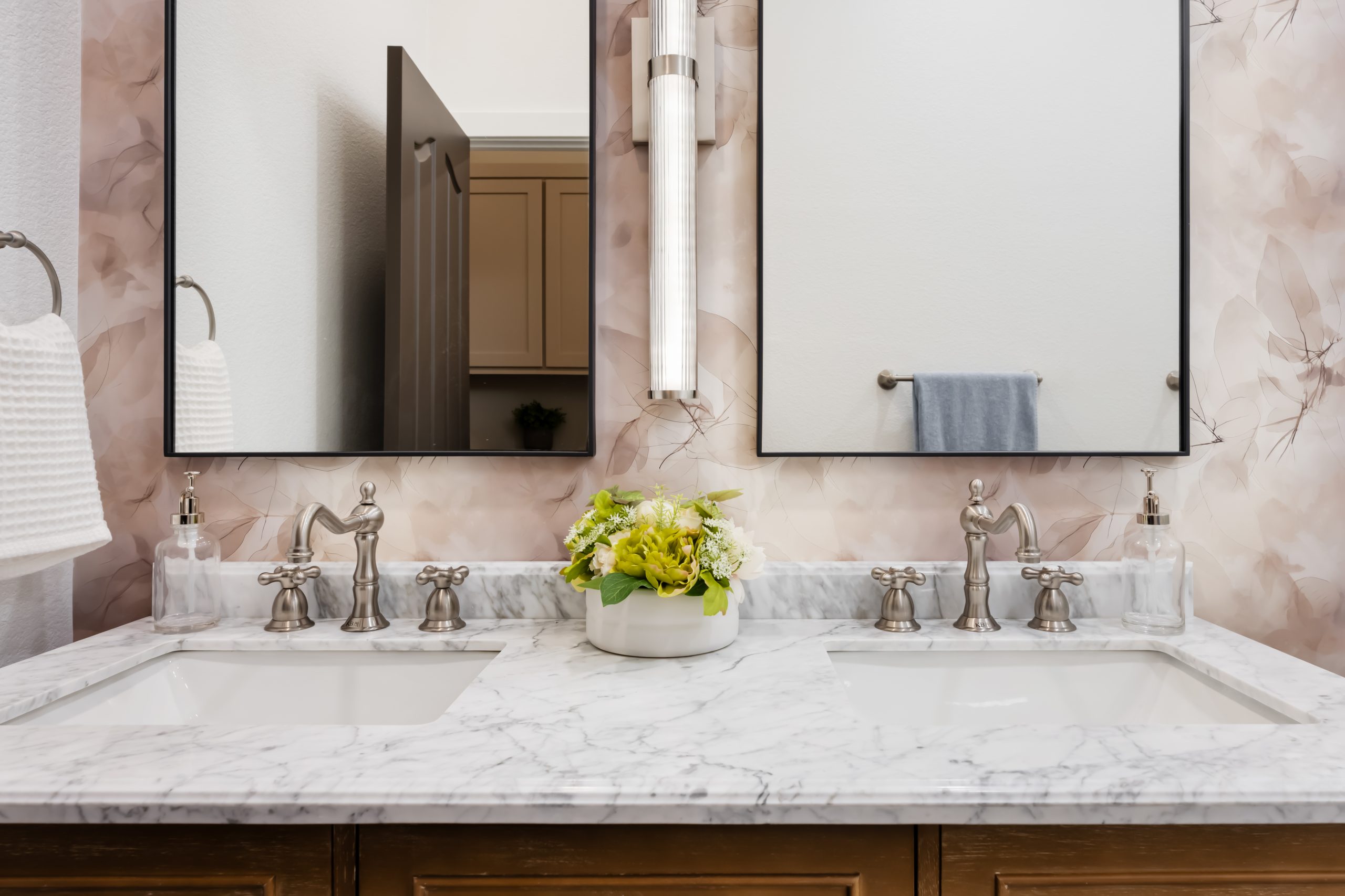 Straight-on dual vanity with Carrara marble and mauve watercolor wallpaper, Kingdom & Co. The Lakes guest bath.