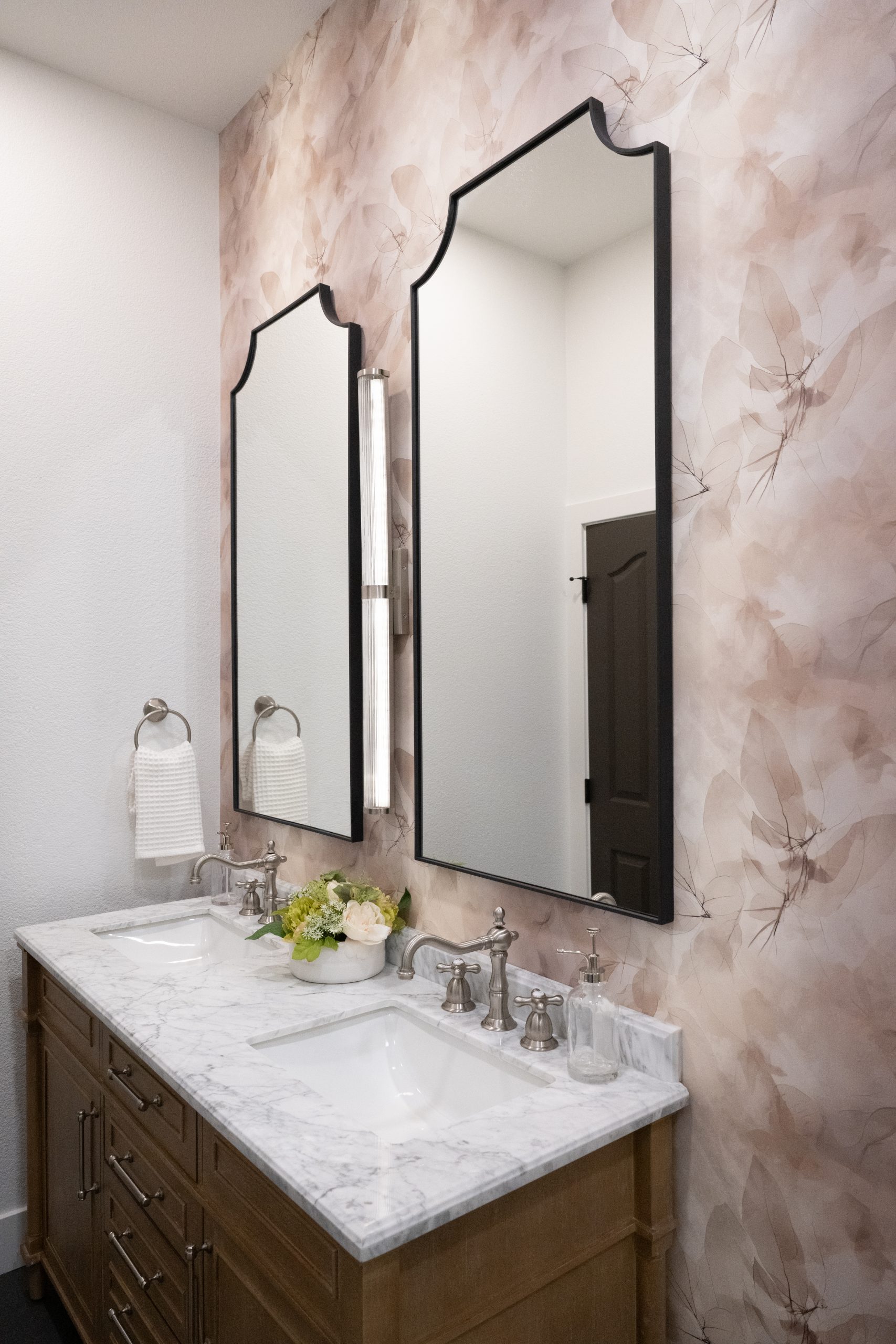 Guest bath dual vanity with black arched mirrors and mauve watercolor wallpaper, Kingdom & Co. The Lakes.