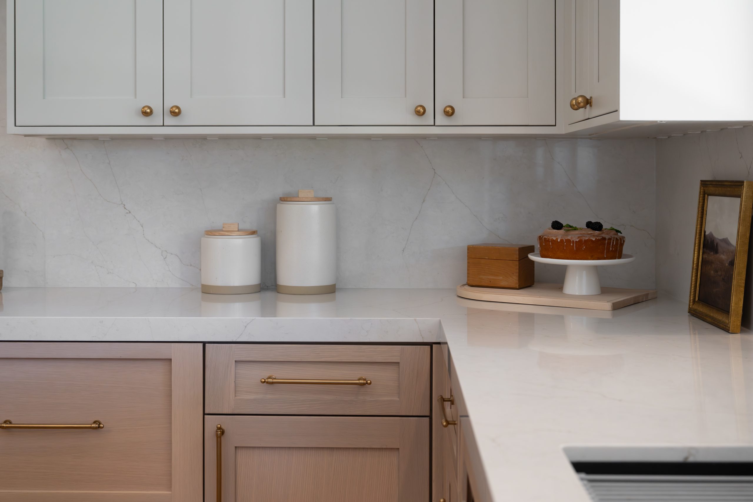 Sourdough cake and canisters on Calacatta quartz counter beside light oak cabinetry, Kingdom & Co. The Lakes kitchen.