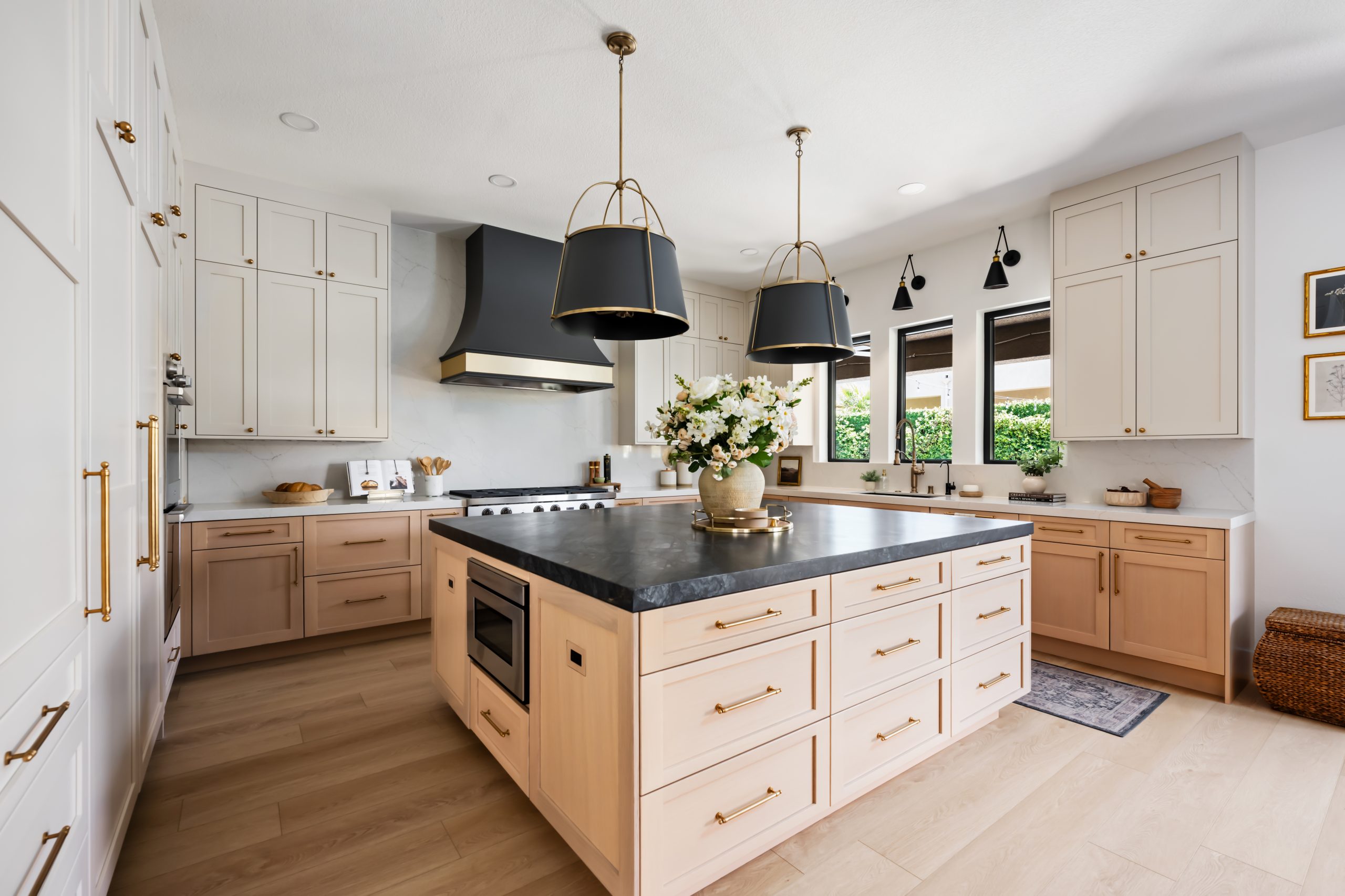 Kitchen hero view with custom hood, black stone island, and panel-front Sub-Zero refrigerator, Kingdom & Co. The Lakes.