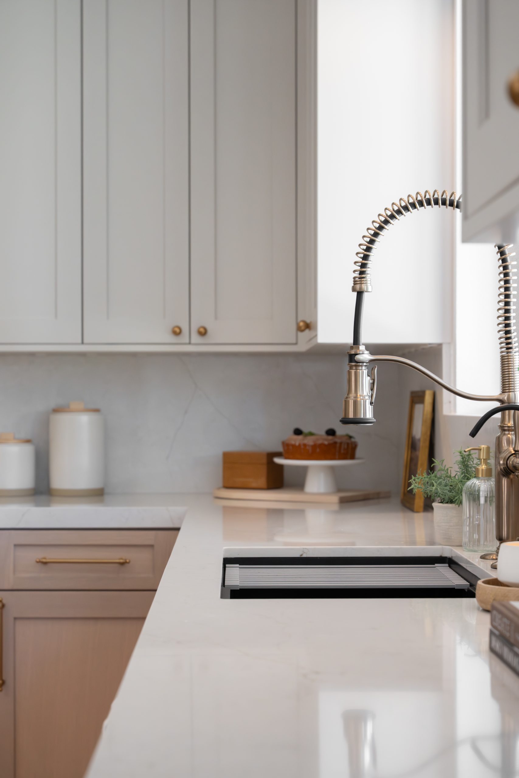 Black workstation sink with brass spring faucet and Calacatta marble backsplash in The Lakes kitchen by Kingdom & Co.
