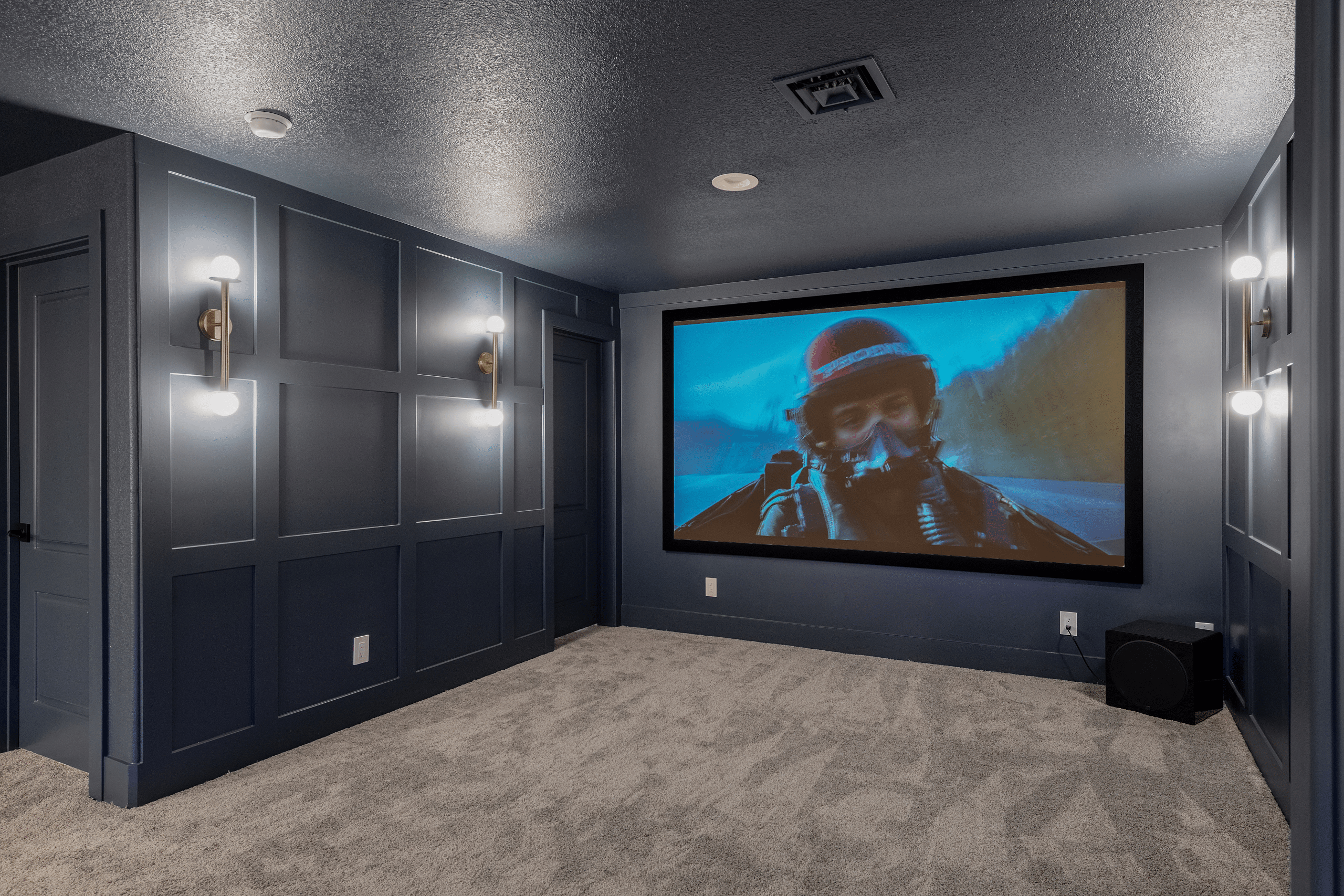 The Ashford (11) Basement movie theater in Willows Summerlin home renovation by Kingdom & Co. — projection screen, tray ceiling, brass double-globe sconces