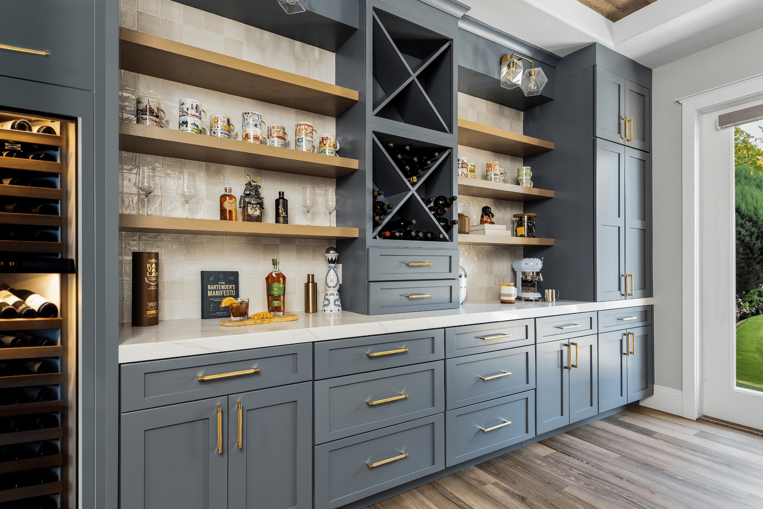 The Ashford (15) Custom dining room bar in Willows Summerlin home renovation by Kingdom & Co. — slate blue cabinets, brass hardware, white oak shelves, wine storage
