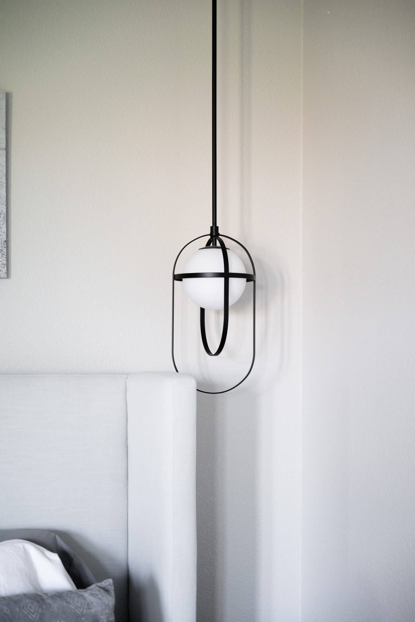 The_Ashford61 Custom black iron oval pendant with milk-glass orb over primary bed in Willows Summerlin home renovation by Kingdom & Co.