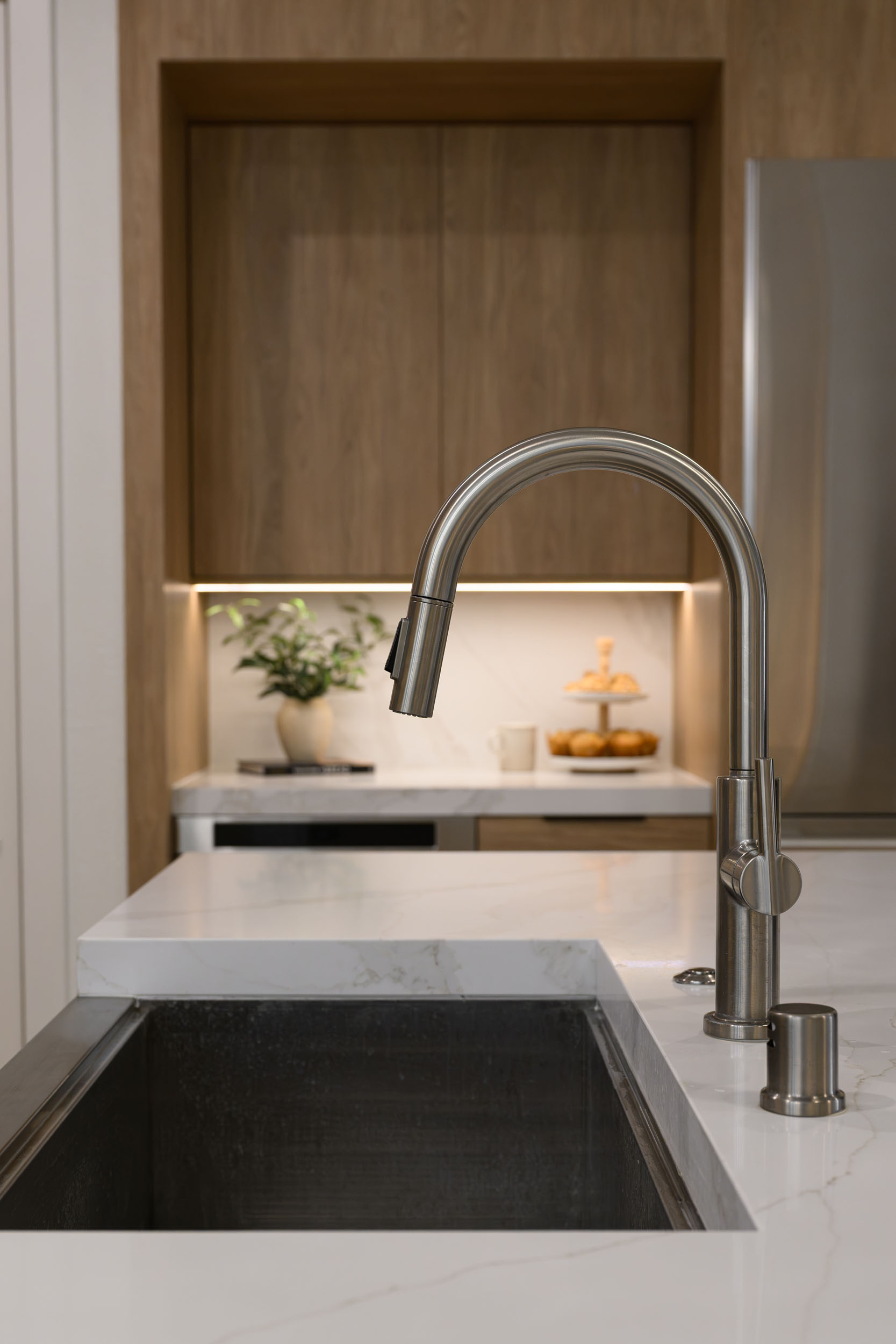 The_Elysian_SummerlinRemodel_Kingdom14 Kitchen apron-front stainless sink detail with tall pull-down faucet on marble waterfall counter in Summerlin remodel by Kingdom & Co.
