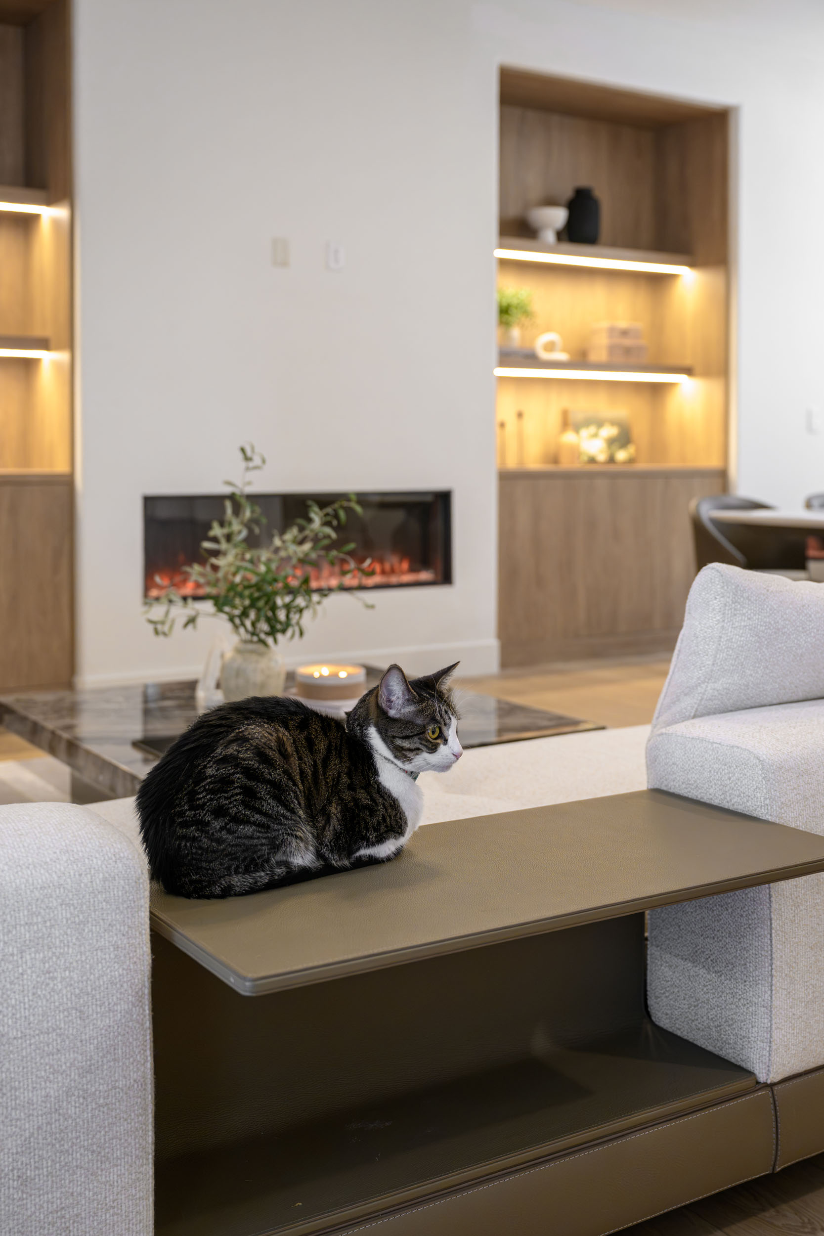 Living room vignette with bouclé sofa, bronze side table, linear gas fireplace, and warm oak built-ins in Summerlin remodel by Kingdom & Co.